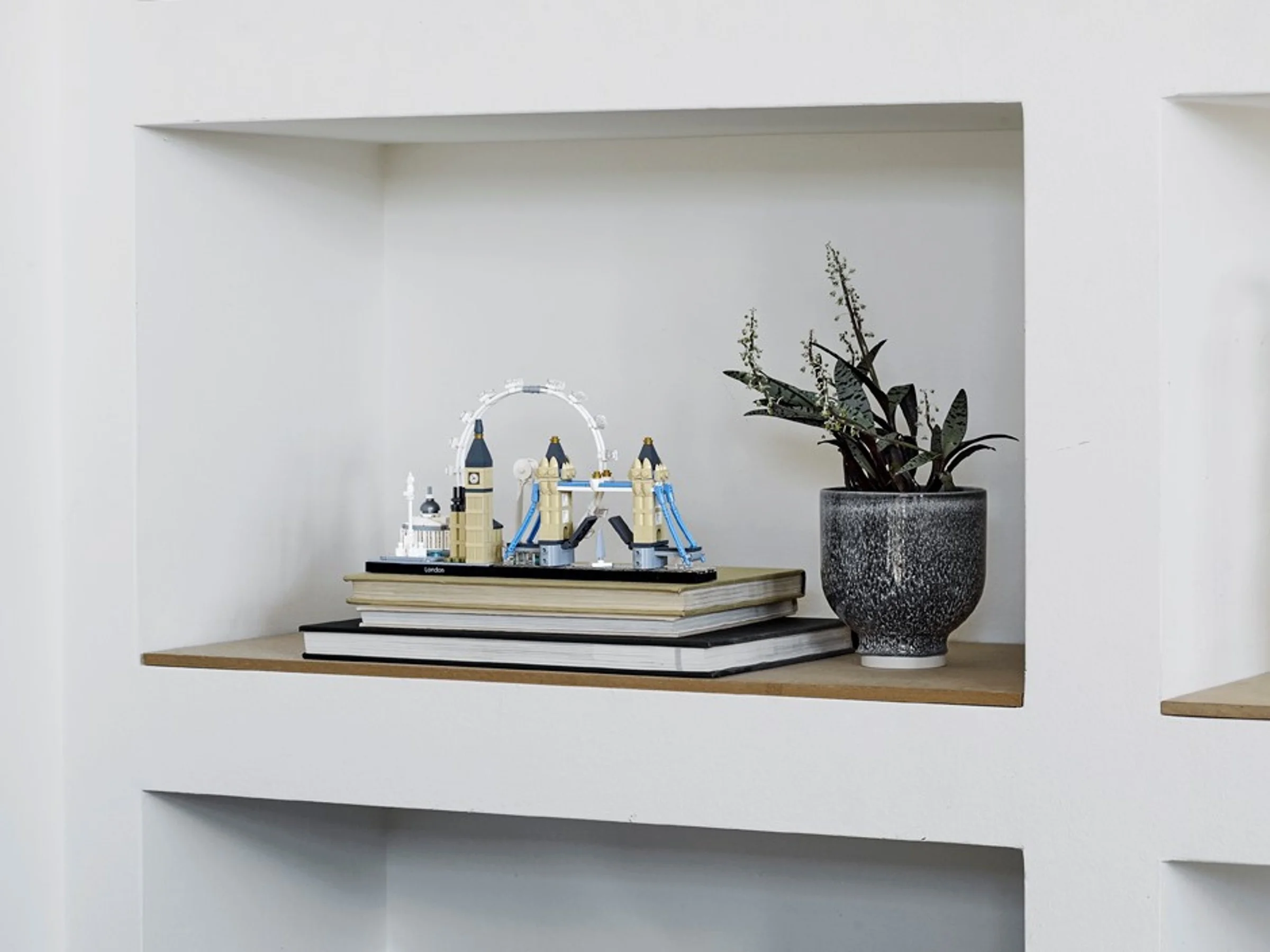 Modelul LEGO Architecture Londra, așezat pe cărți, într-o nișă modernă. Decorațiune interioară elegantă.