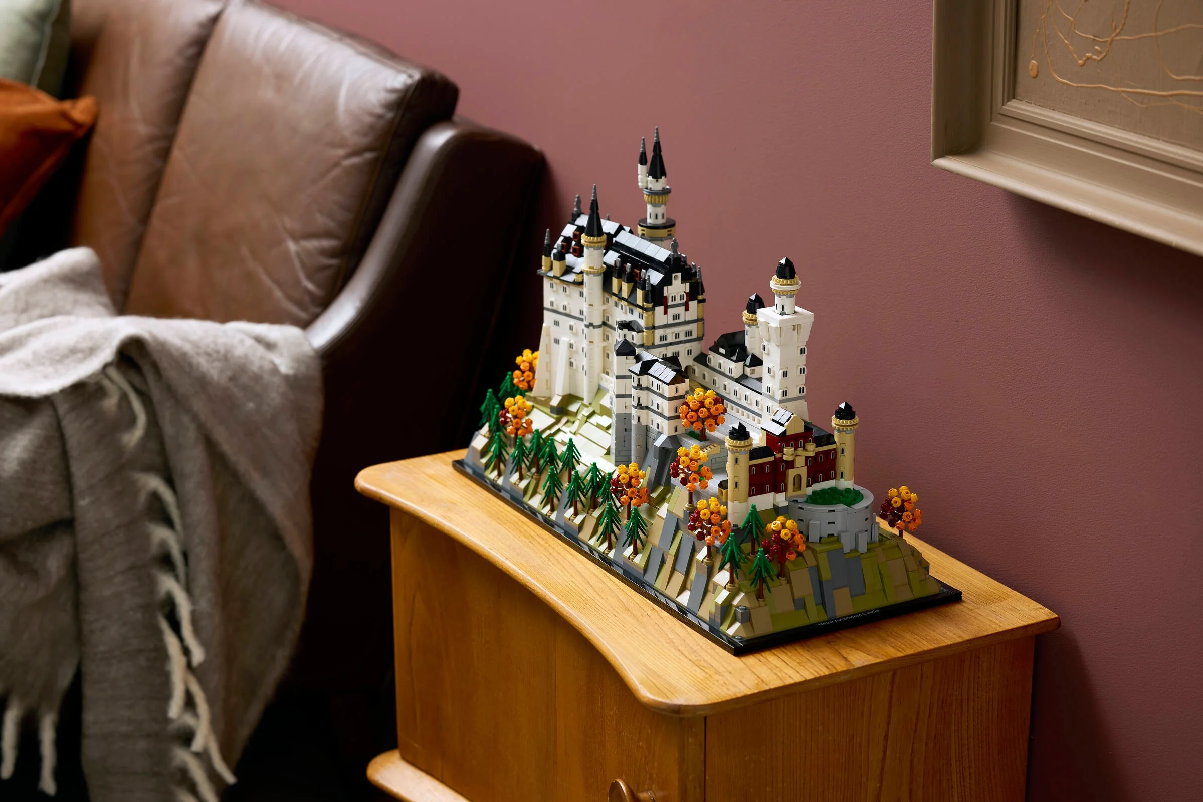Castelul Neuschwanstein LEGO, un model detaliat expus pe o comodă elegantă, într-o cameră decorată modern.