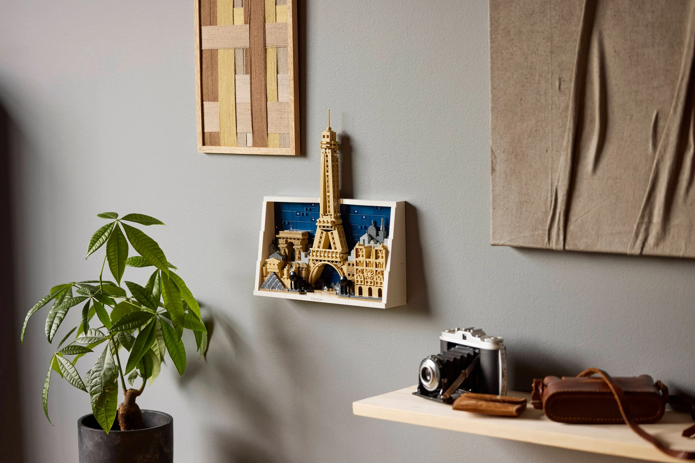 Modelul LEGO Paris expus pe un perete, alături de alte obiecte decorative. Frumos și elegant.