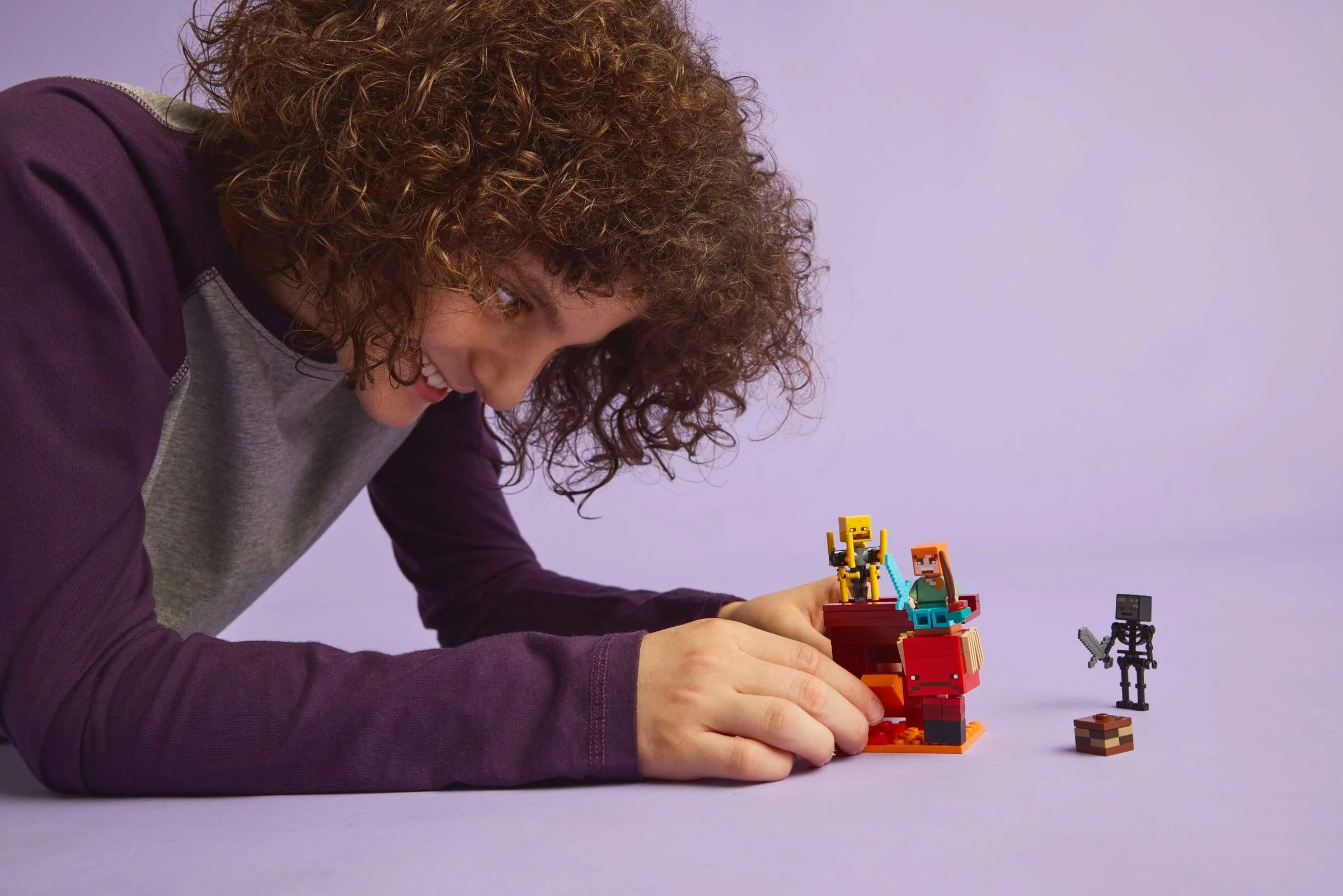 Imagine cu copil construind setul LEGO Minecraft 21266, cu minifigurinele și structura de lavă.