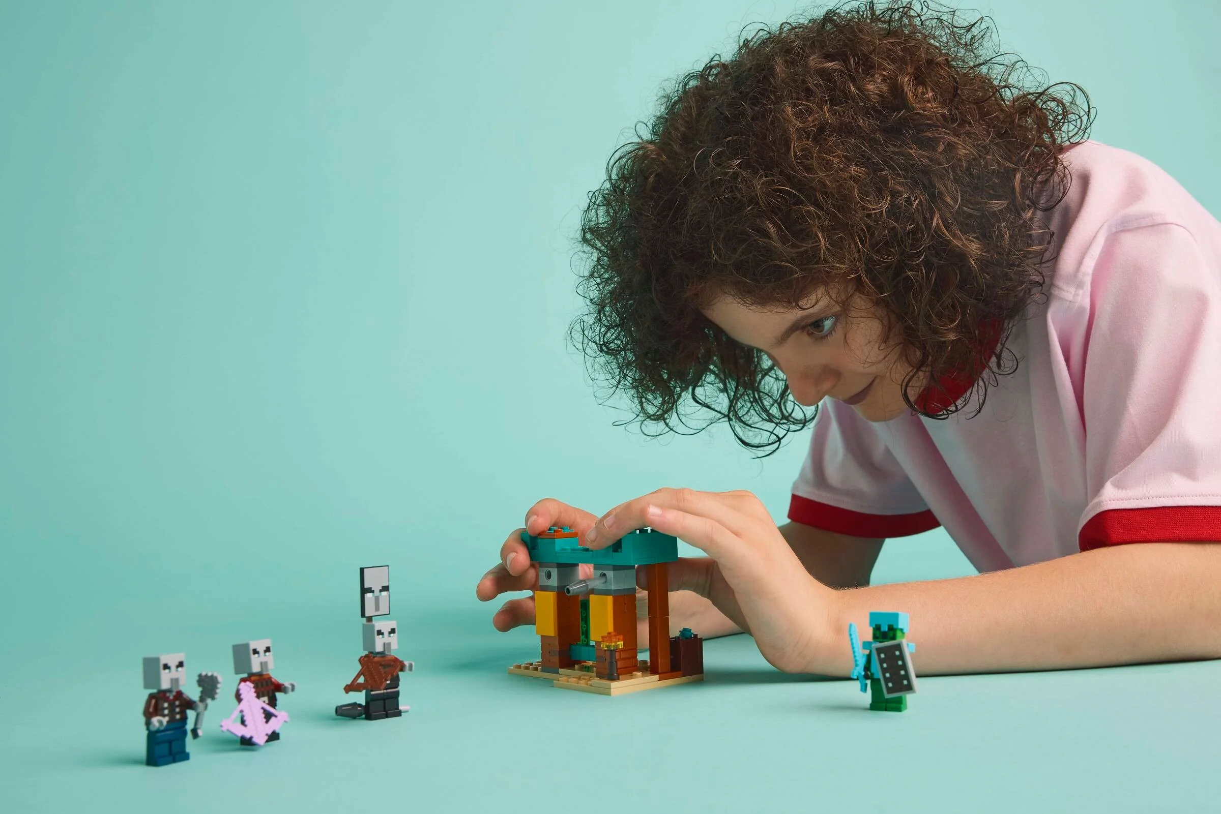 Copil construind setul LEGO Minecraft 21267. Patrula Illager în deșert, o scenă plină de aventură.