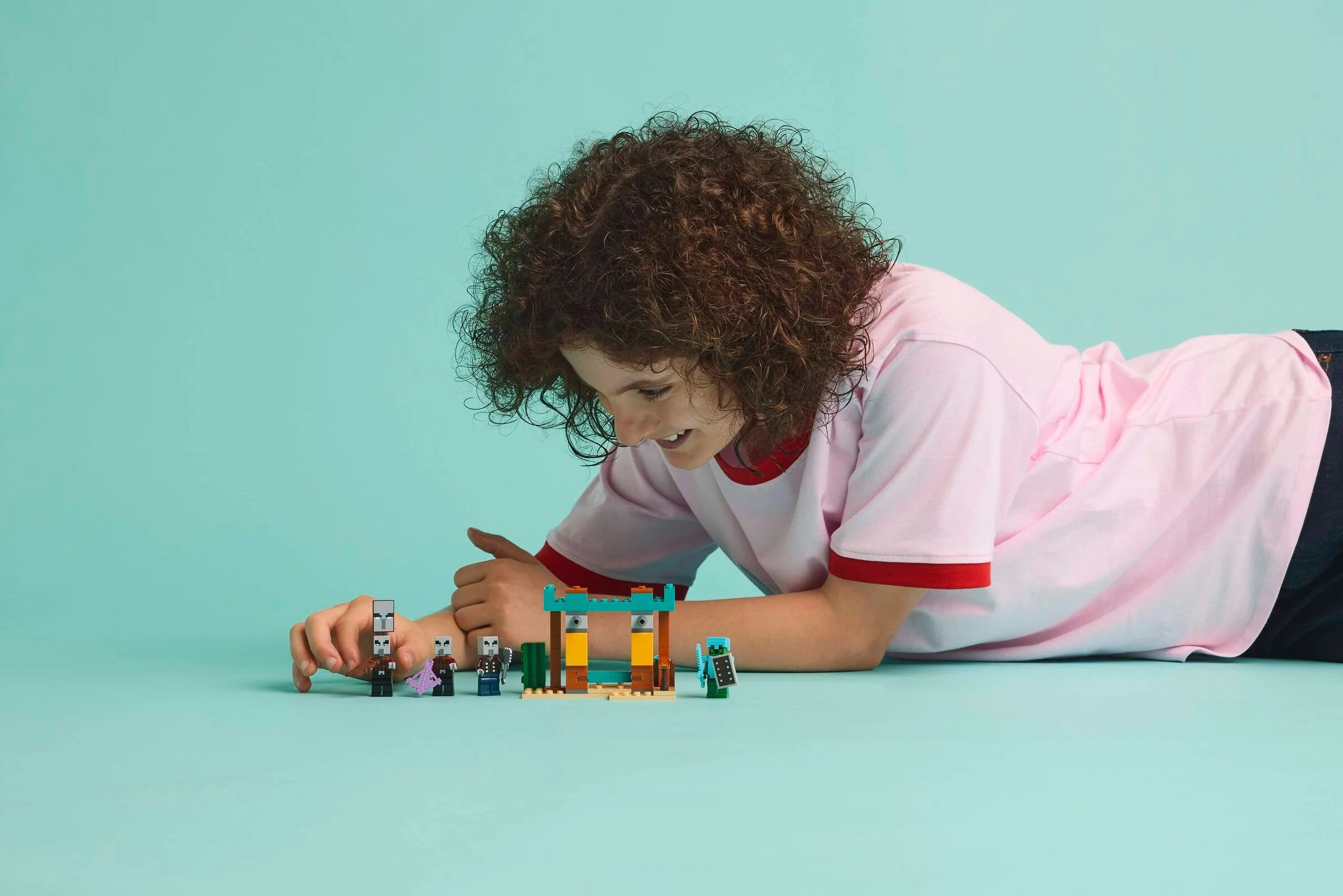 Copil se joacă cu setul LEGO Minecraft 21267. Distracție în deșert cu figurinele Illager.