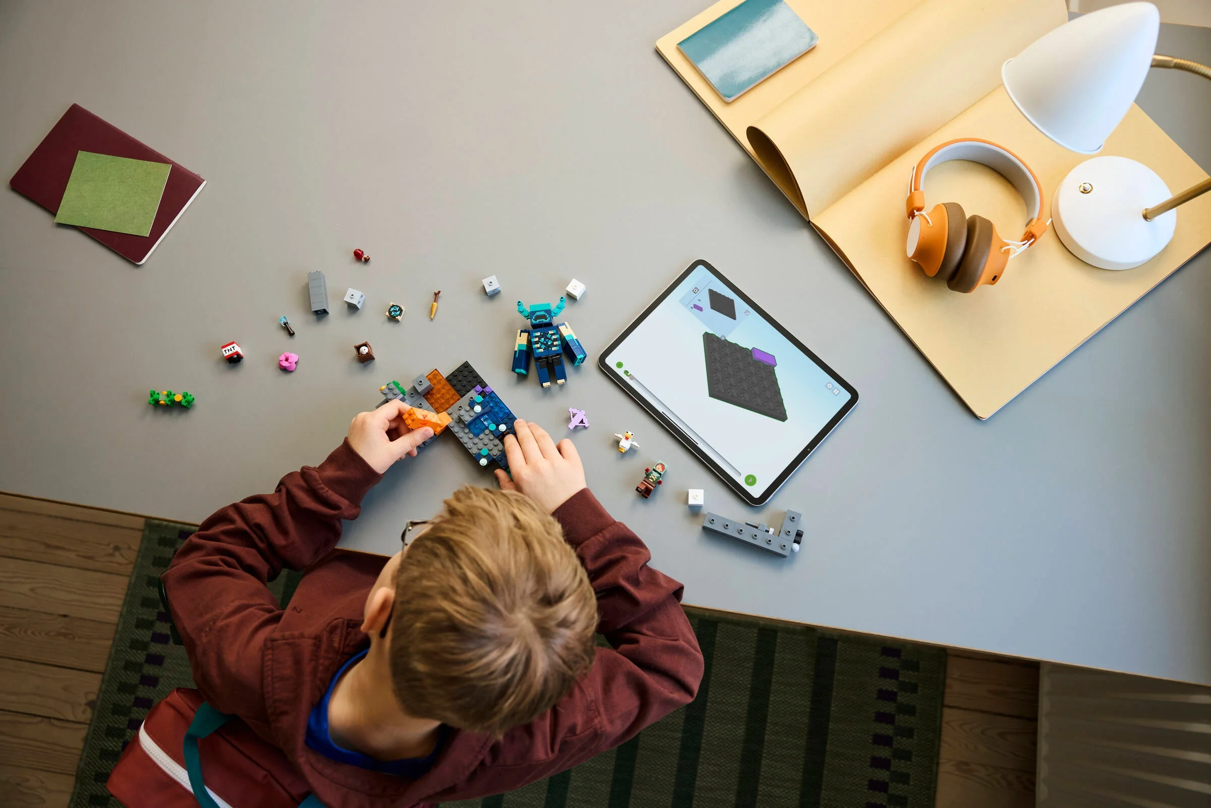 Băiat construind setul LEGO Minecraft 21274, cu aplicația de instrucțiuni pe tabletă.