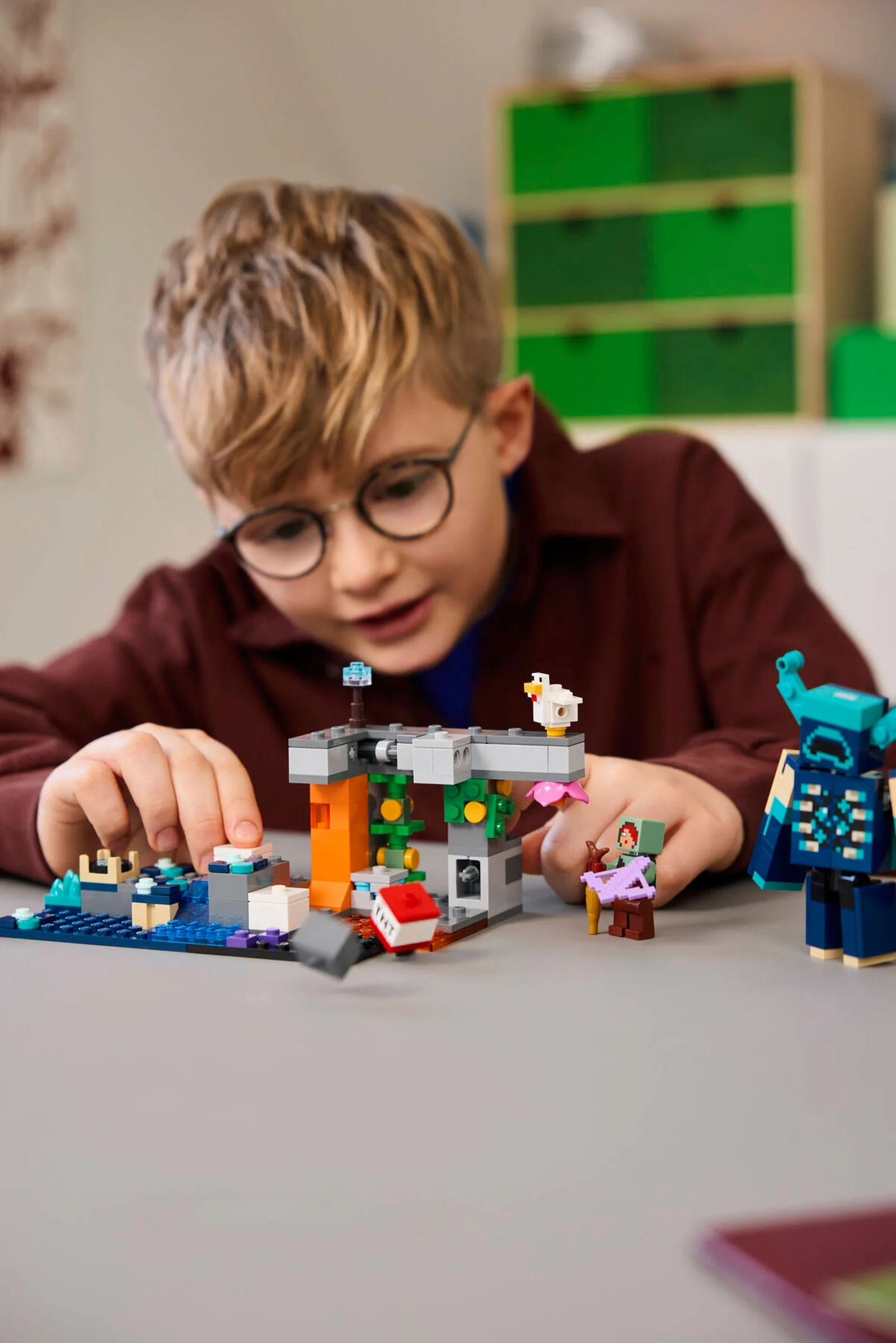 Un copil se joacă cu setul LEGO Minecraft 21274, cu Warden și alte minifigurine.