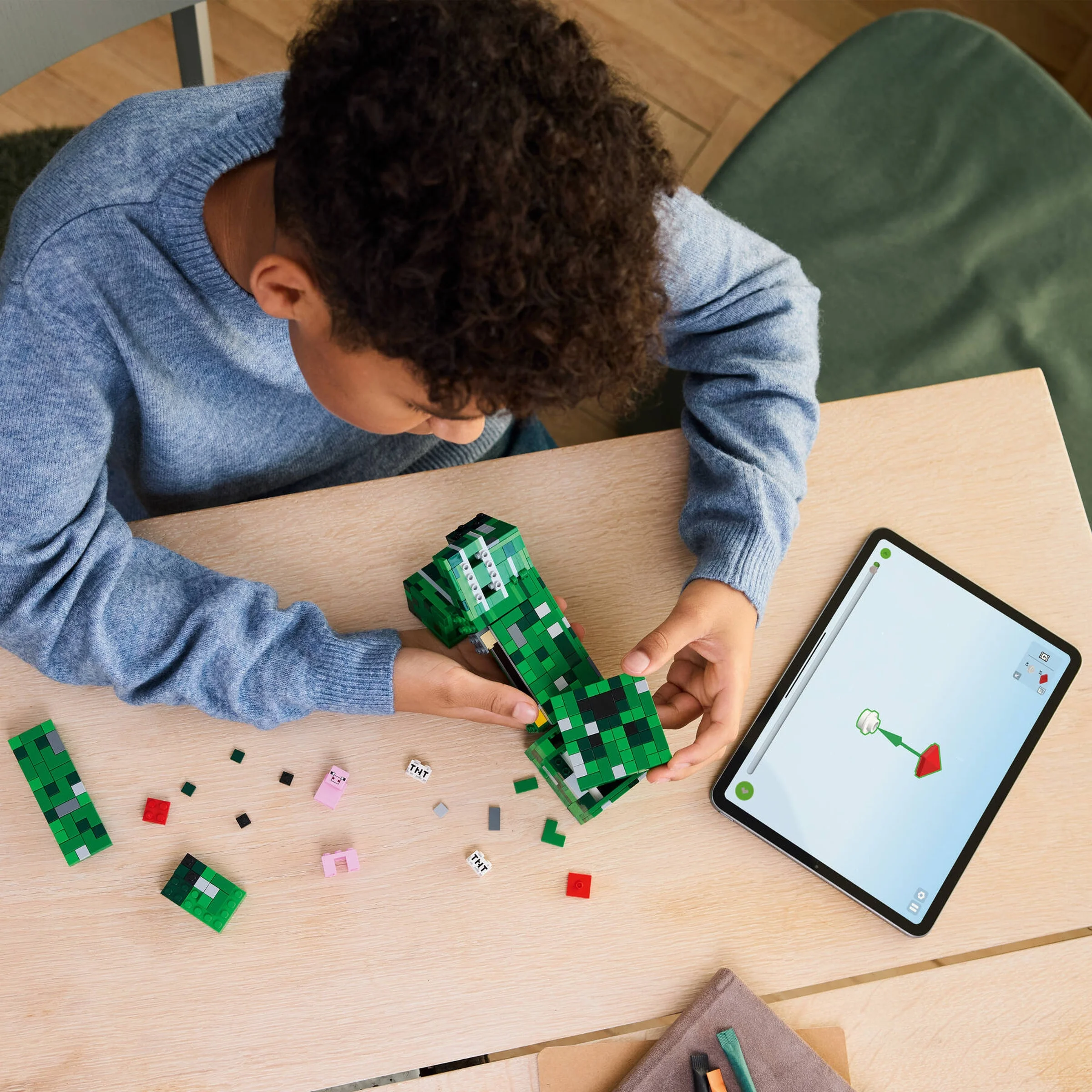 Copil construind Creeper-ul LEGO Minecraft 21276. Instrucțiuni digitale pe tabletă.