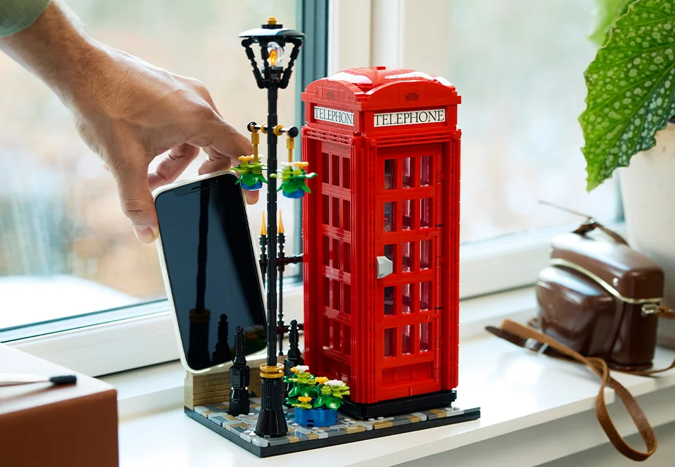 Imagine cu cabina telefonică roșie LEGO, o lampă stradală și un telefon, într-un cadru de viață.