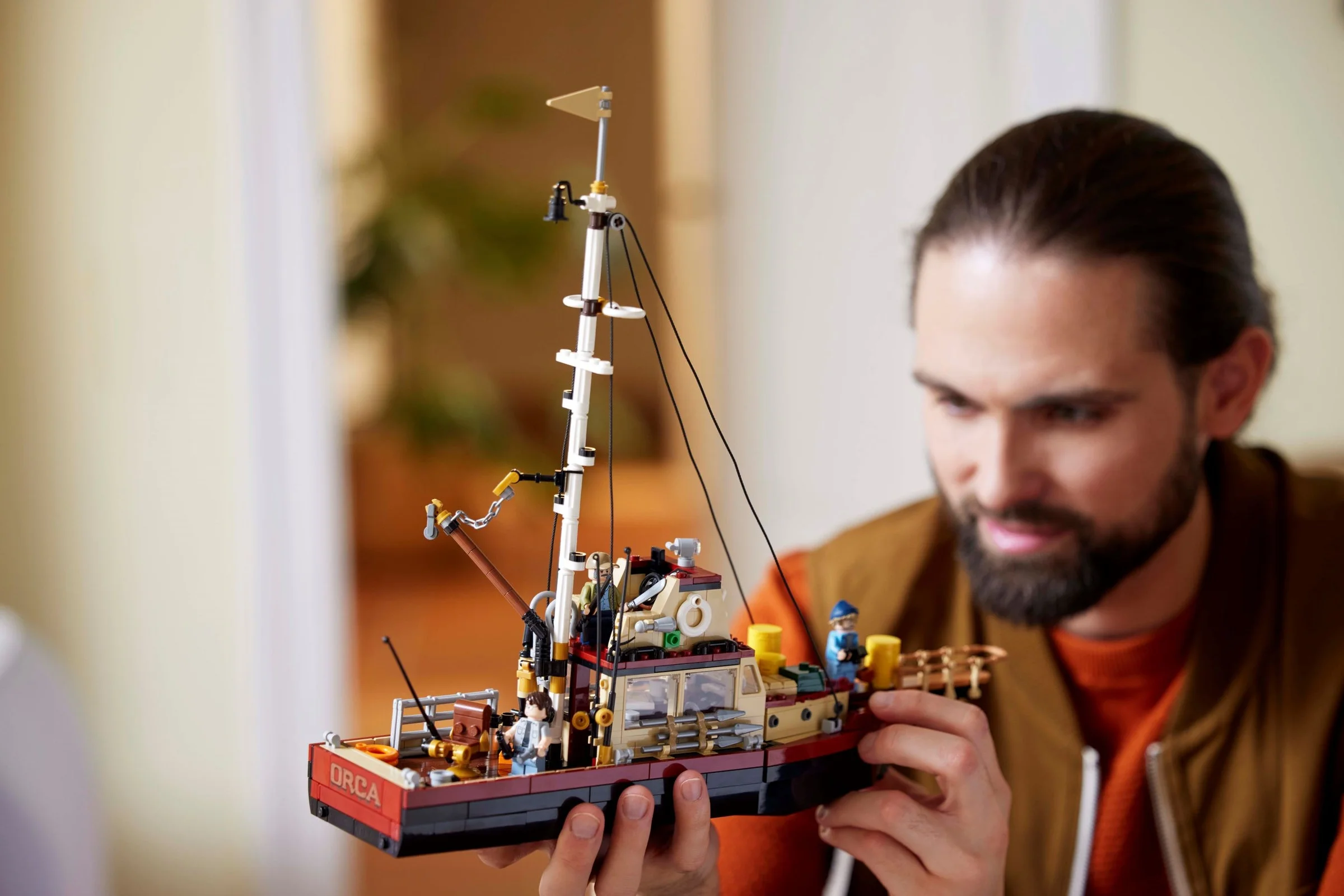 Un adult admiră setul LEGO Jaws, Orca, în mâini. Un cadru luminos și plăcut.