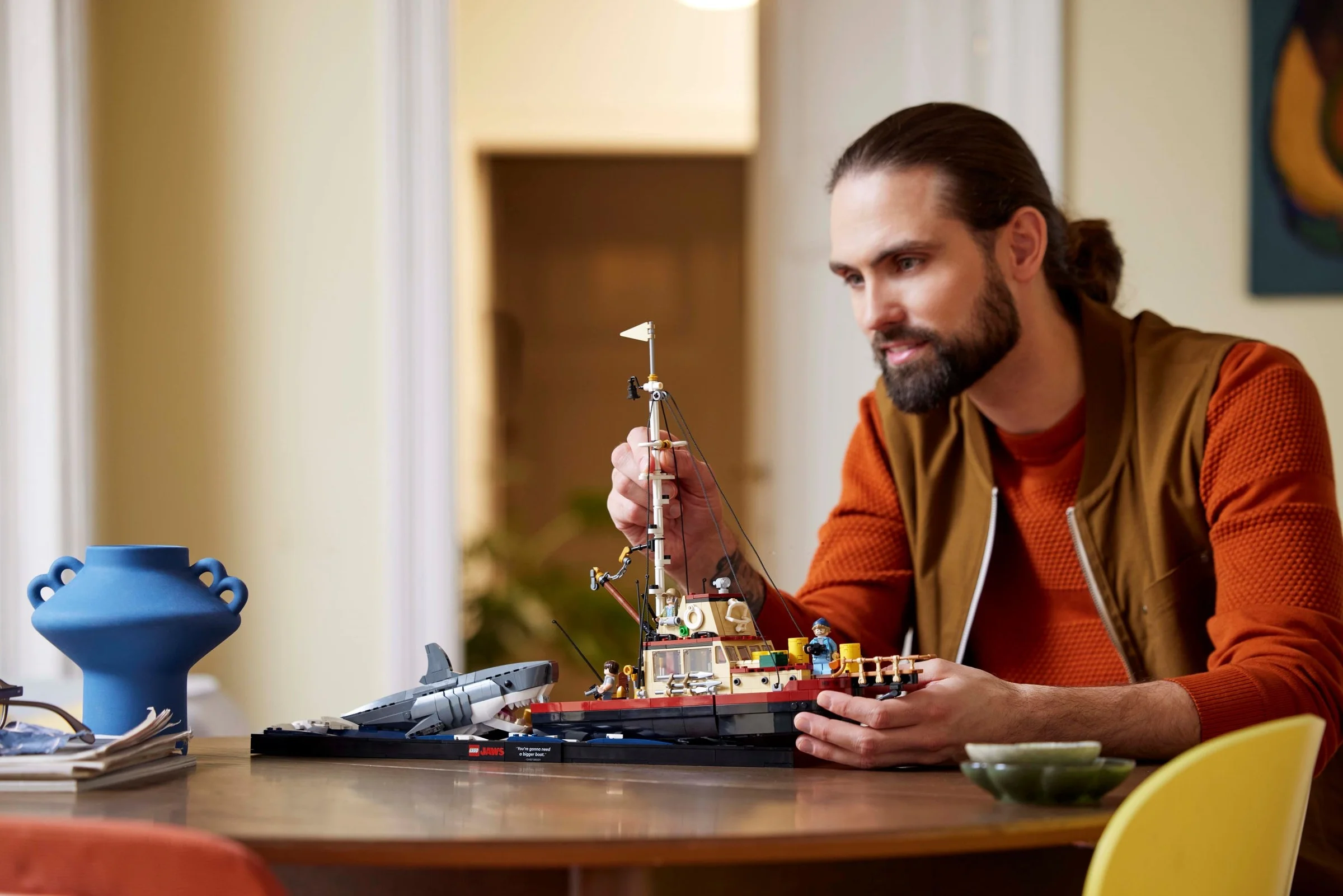 Bărbat construind setul LEGO Jaws (21350), imagine tip stil de viață.