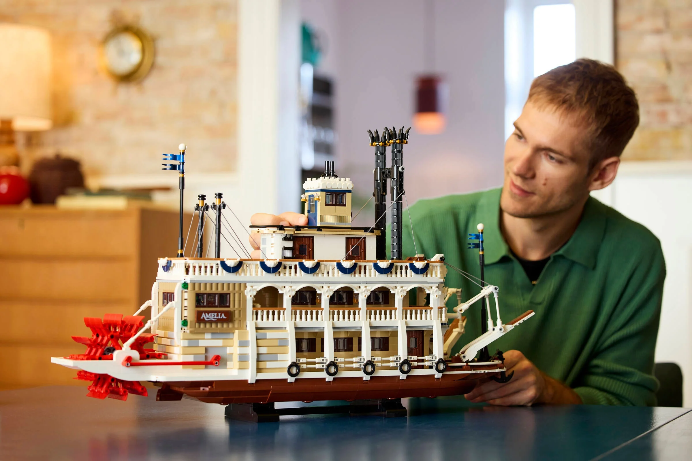Bărbat admirând vaporul cu zbaturi LEGO River Steamboat, o replică detaliată și elegantă.