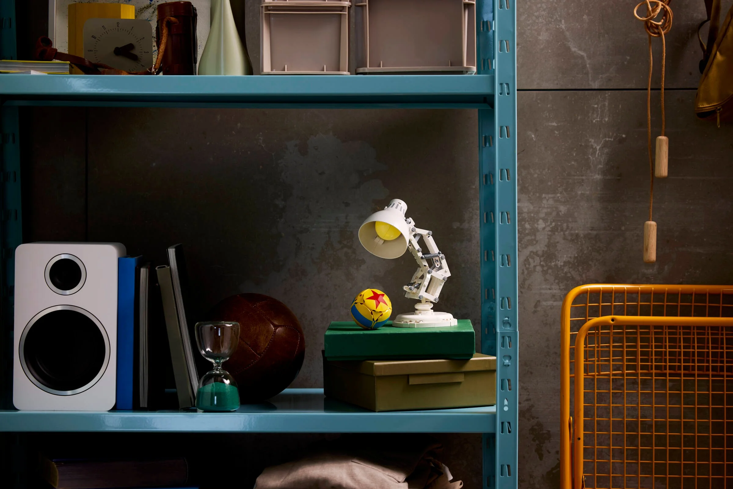 Luxo Jr. LEGO pe un raft cu diverse obiecte, ambient creativ.