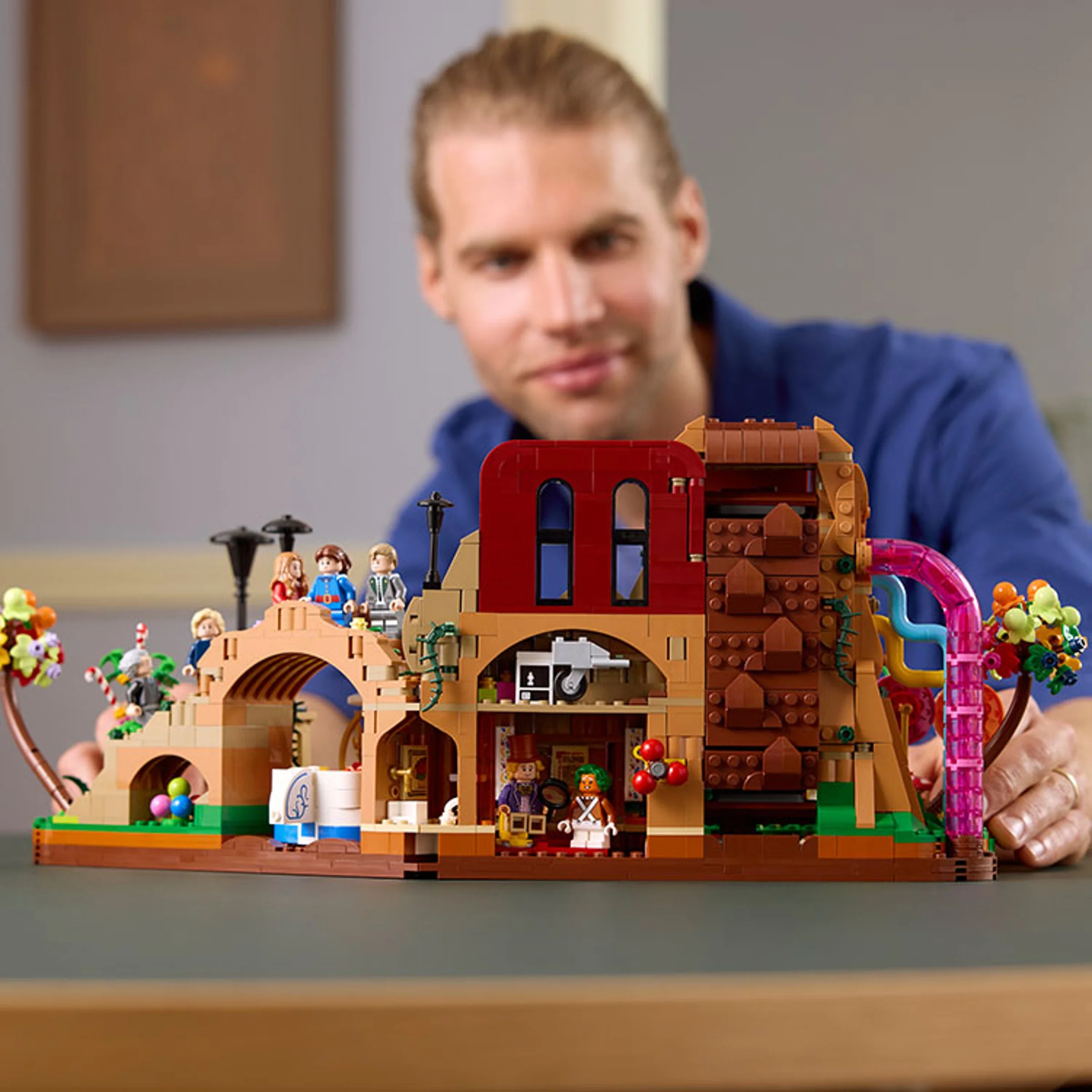 Modelul LEGO Willy Wonka, cu minifigurinele și detalii ale fabricii, prezentat de un adult.