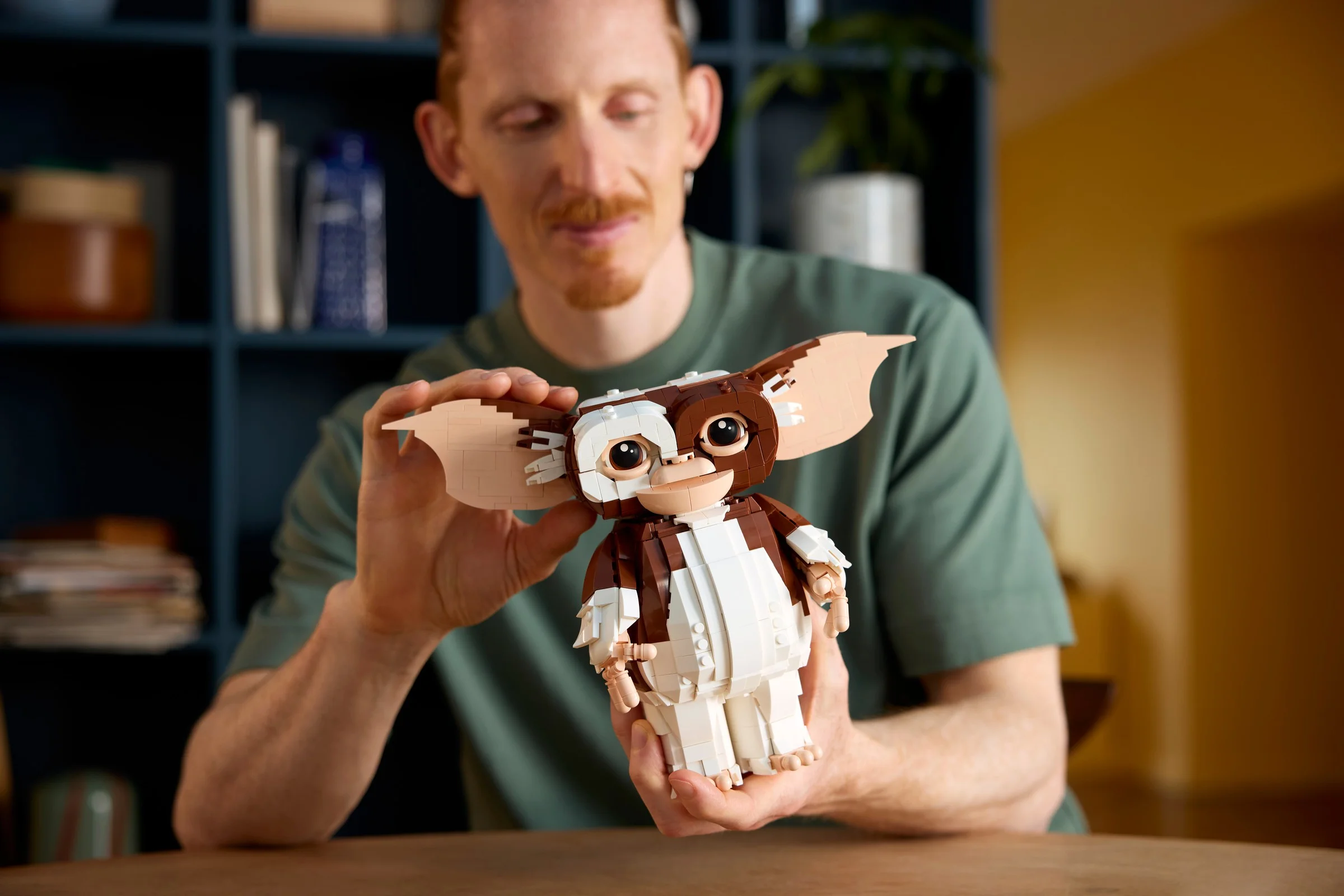 Un adult admiră figurina LEGO Gizmo, zâmbind și ținând-o în mâini.