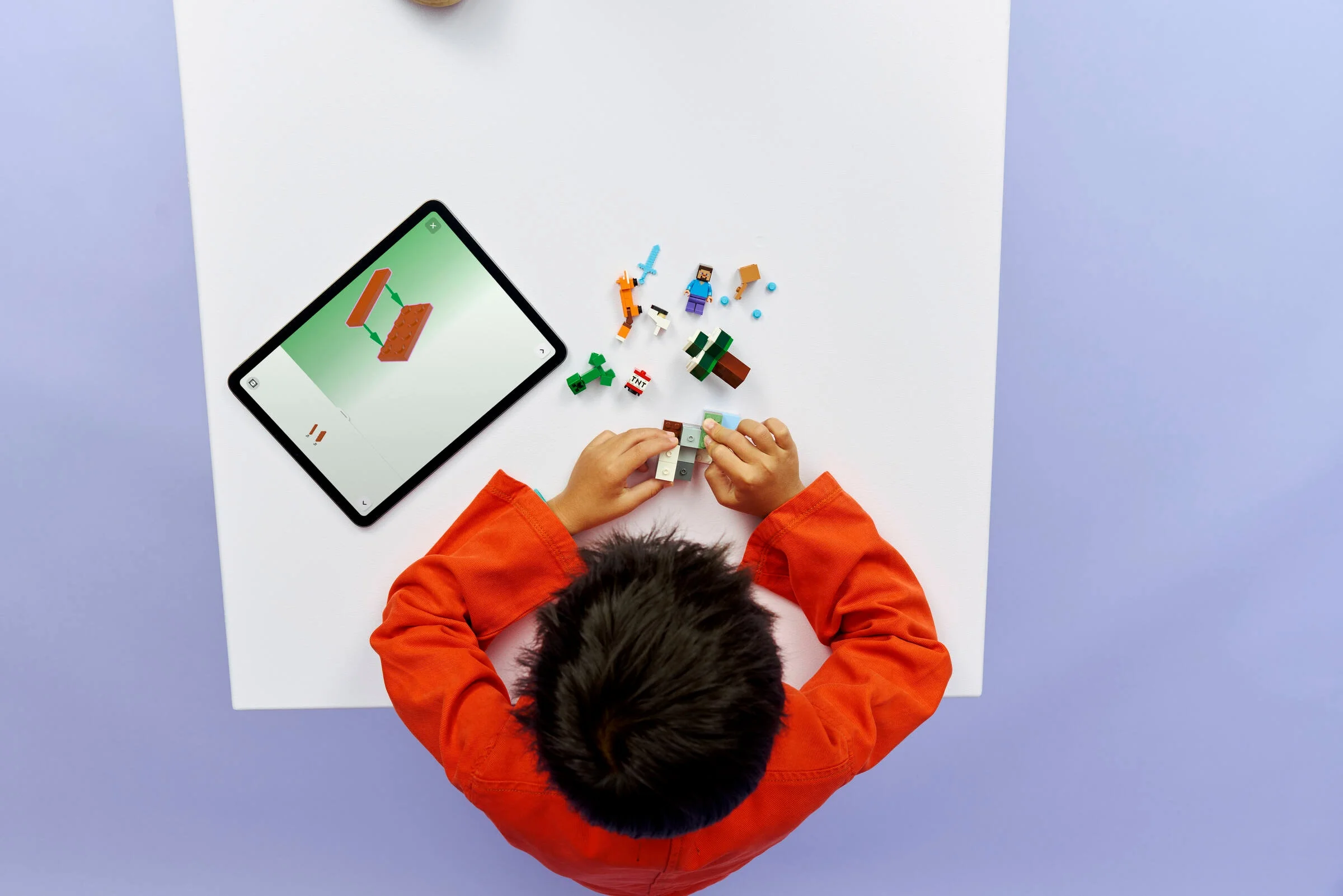 Copil construind setul LEGO Minecraft 21583, urmărind instrucțiunile de pe tabletă.
