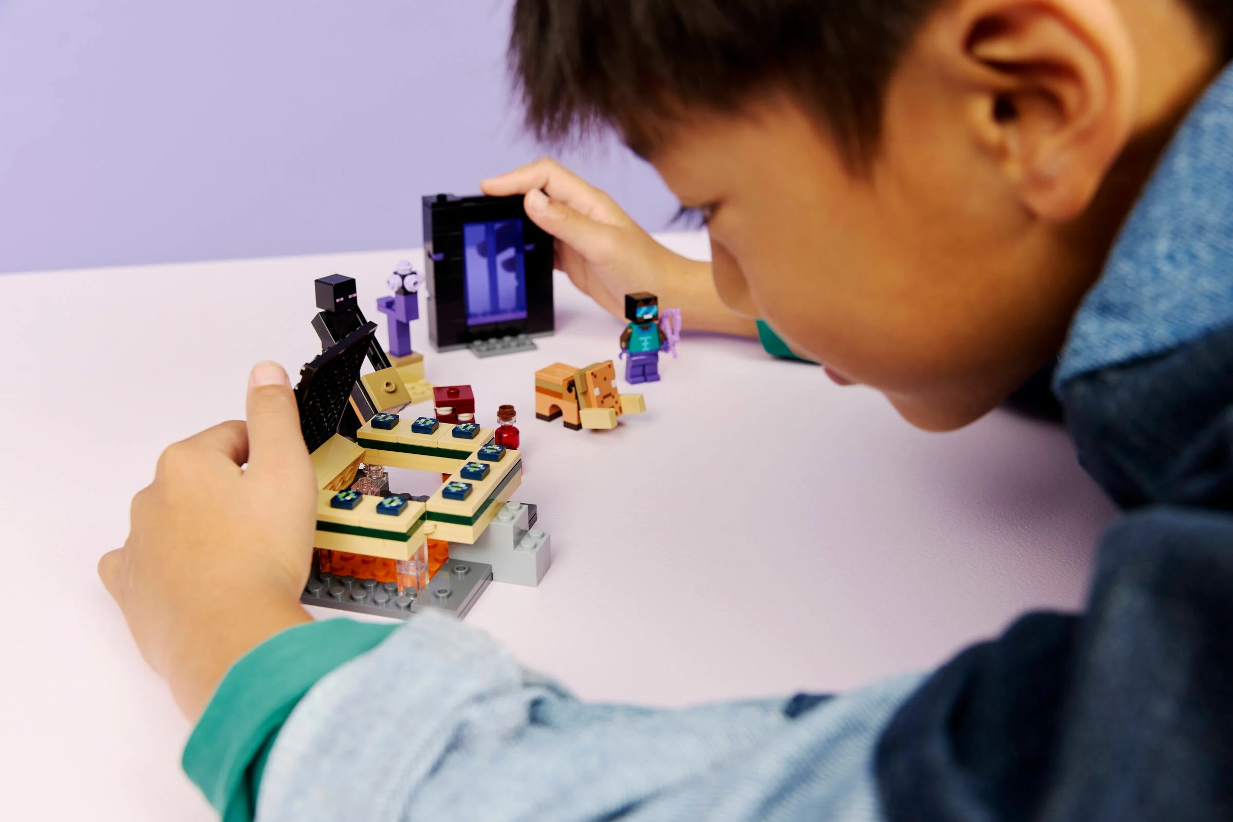 Copil construind portalul Nether și End. Set Minecraft LEGO 21584.