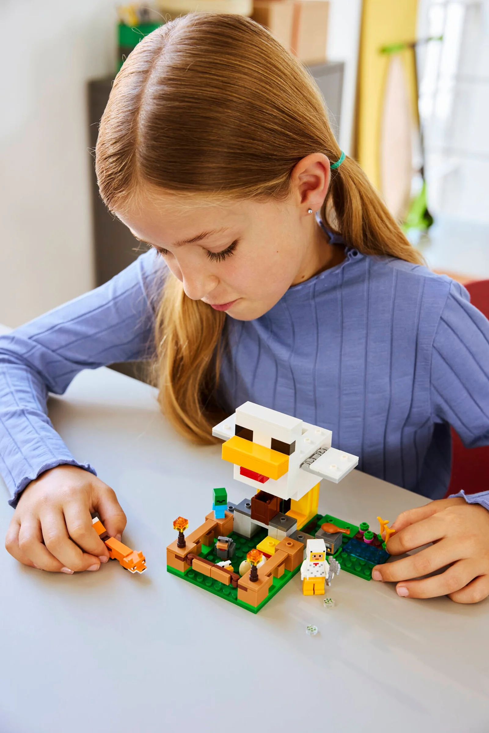 O fată construiește ferma de găini LEGO Minecraft. Set atractiv și detaliat.