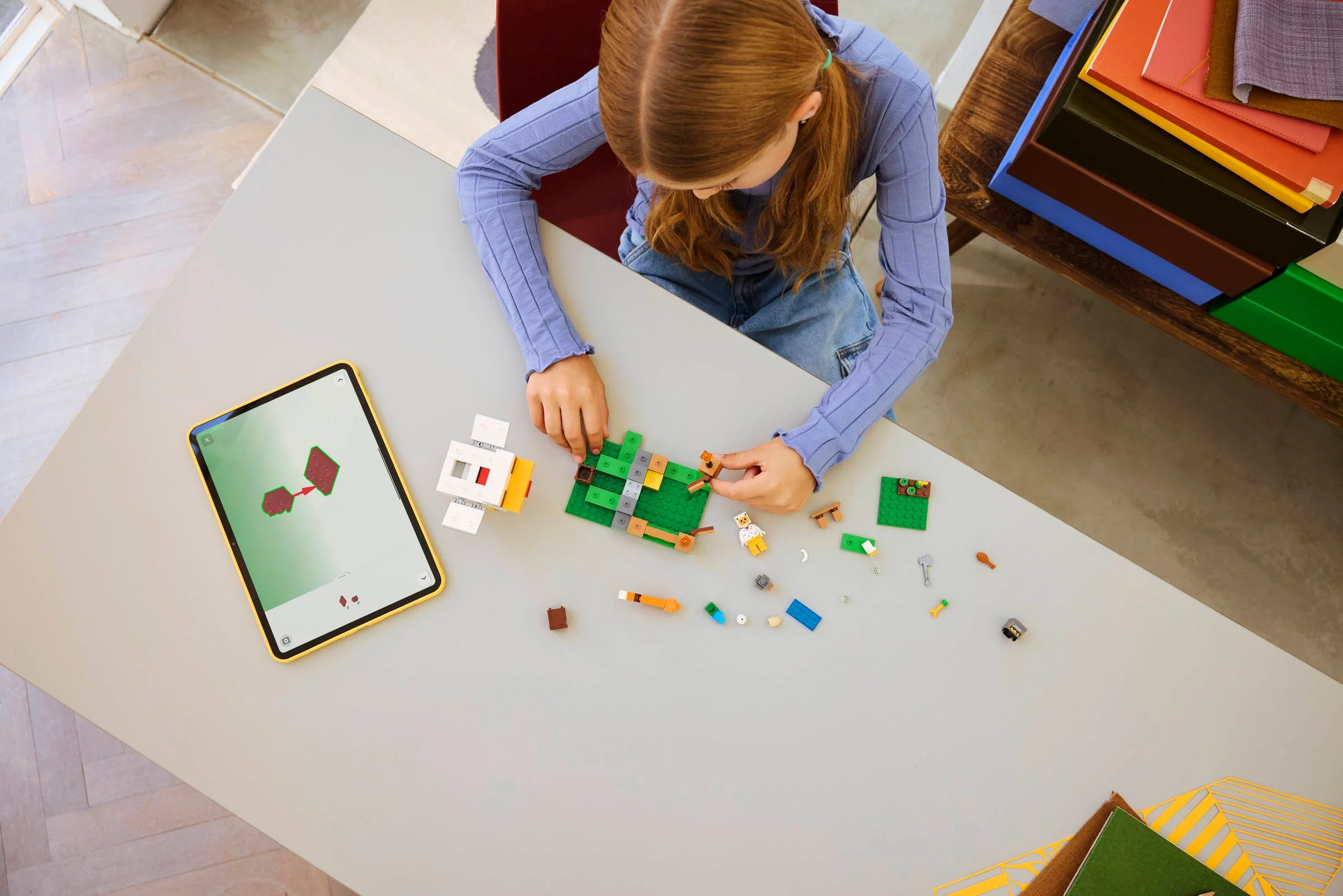 Fată construind ferma de găini LEGO Minecraft, urmând instrucțiuni de pe tabletă.