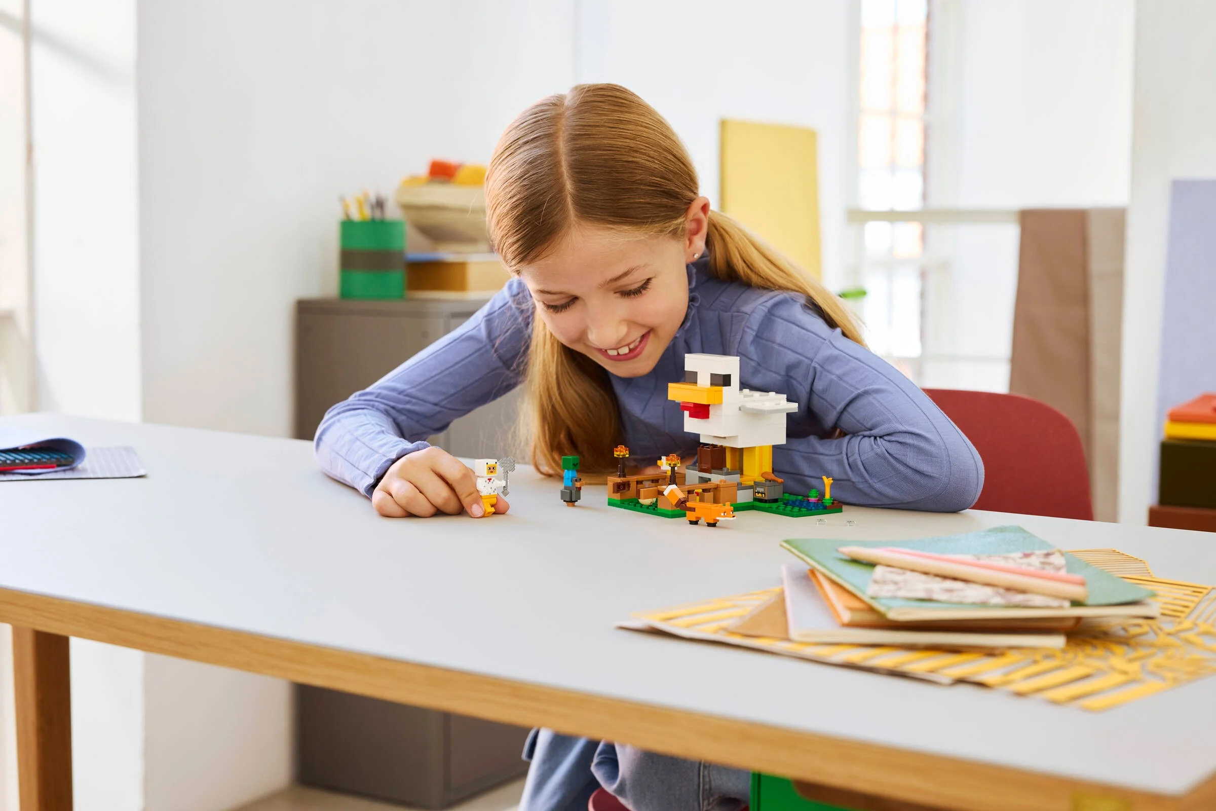 Fetiță zâmbitoare se joacă cu LEGO Minecraft Ferma de găini. Set creativ, distractiv.