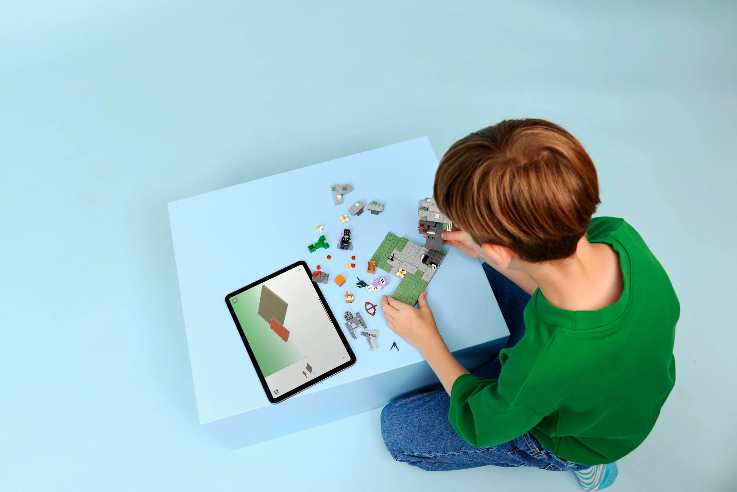 Copil construind setul LEGO Minecraft „Grădina Palidă”. Instrucțiuni digitale pe tabletă.