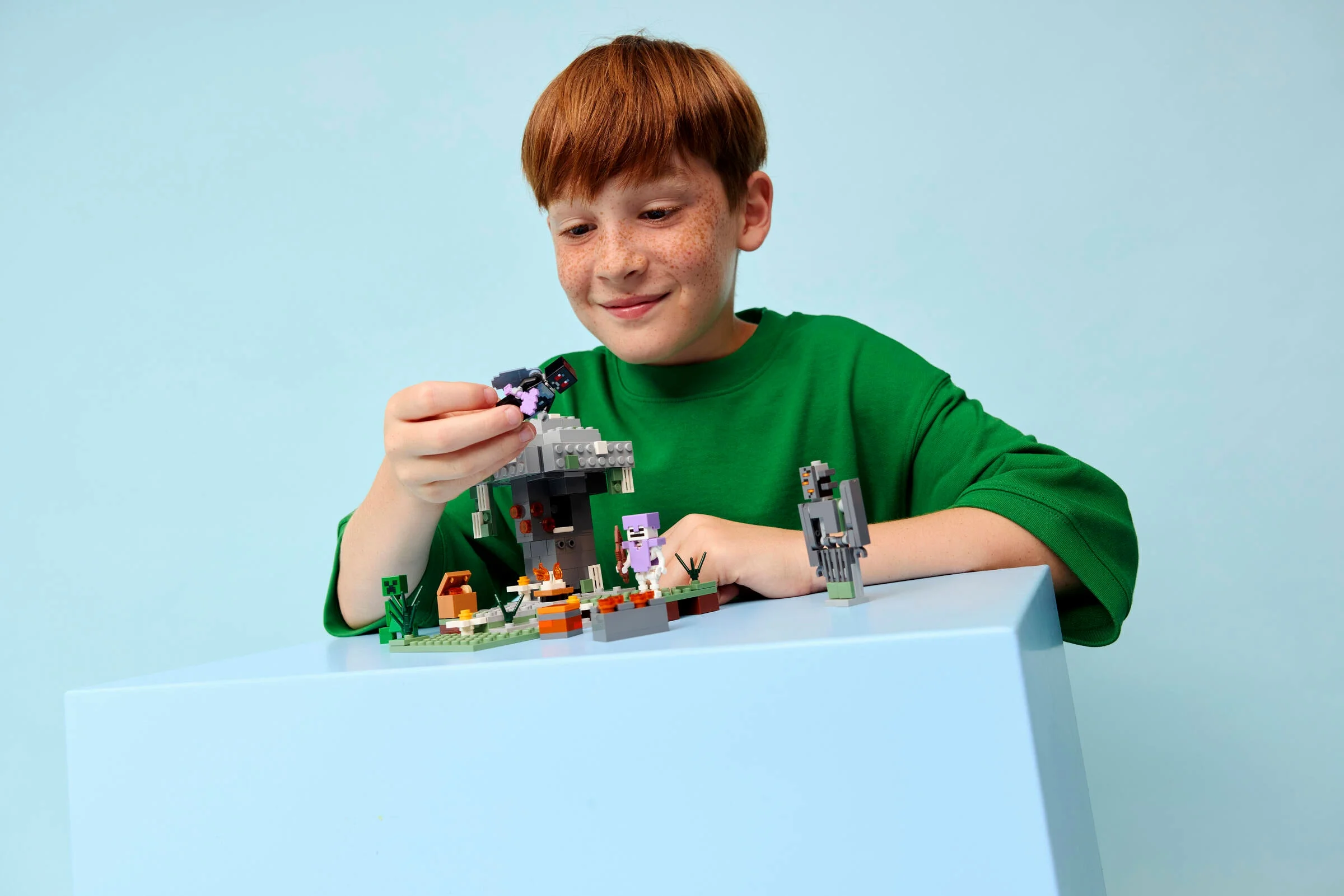 Un copil se joacă cu setul LEGO Minecraft „Grădina Pale”. Setul include un golem, un schelet și alte elemente.