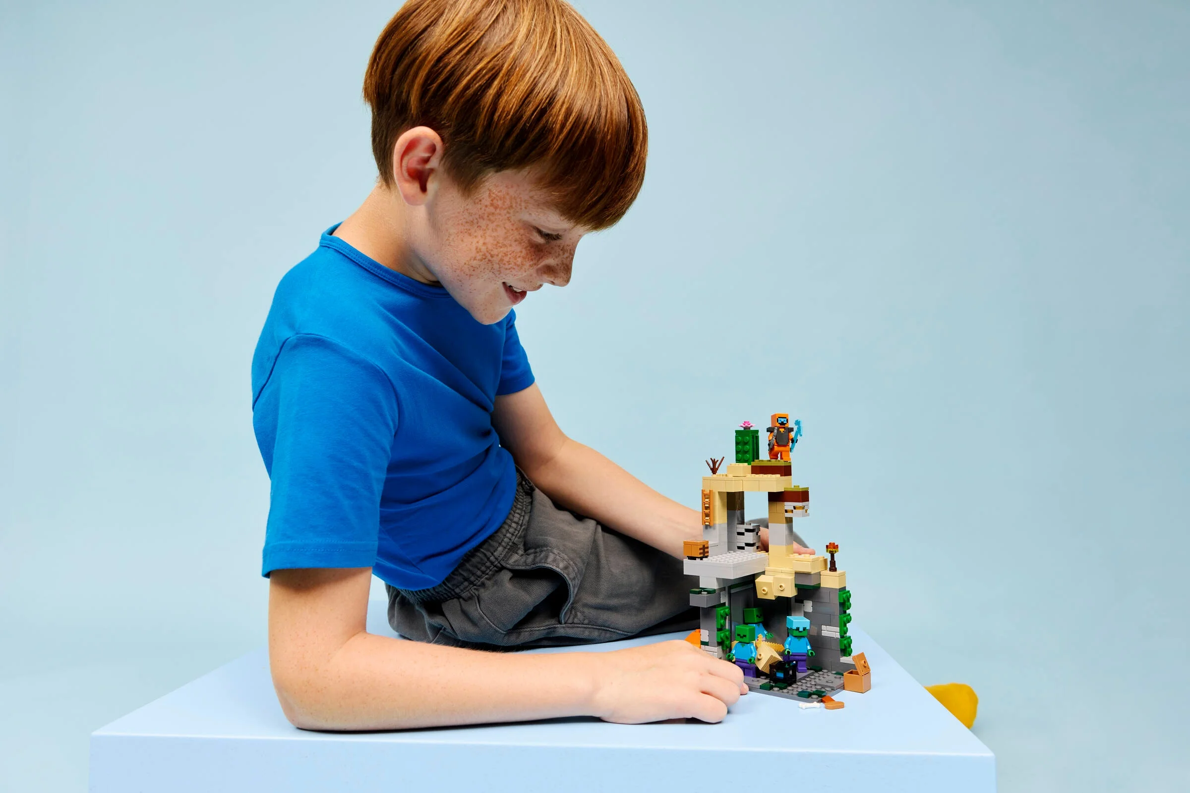 Băiat se joacă cu setul LEGO Minecraft „Zombie Dungeon”. Imagine cu modelul construit.