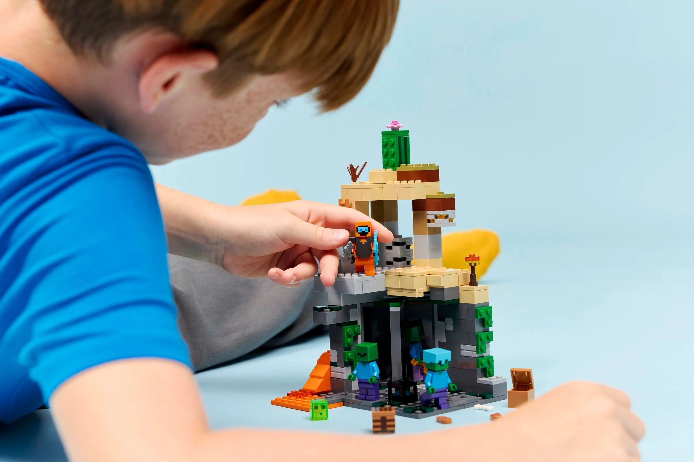 Copil construind setul LEGO Minecraft 21587 cu minifigurine și detalii din joc.