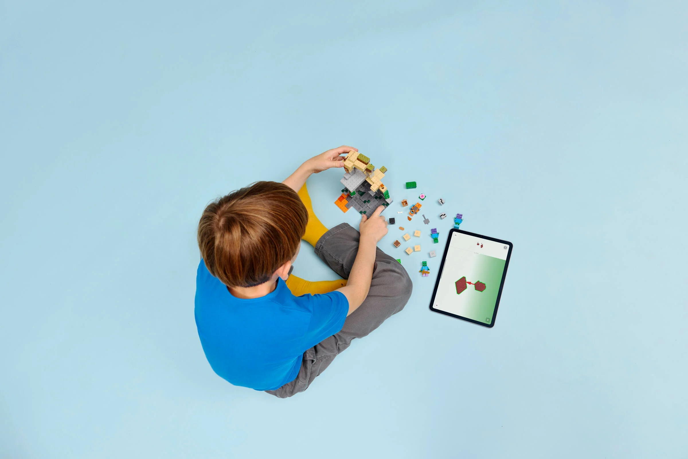 Copil construind setul LEGO Minecraft Zombie Dungeon, folosind instrucțiuni digitale pe tabletă.
