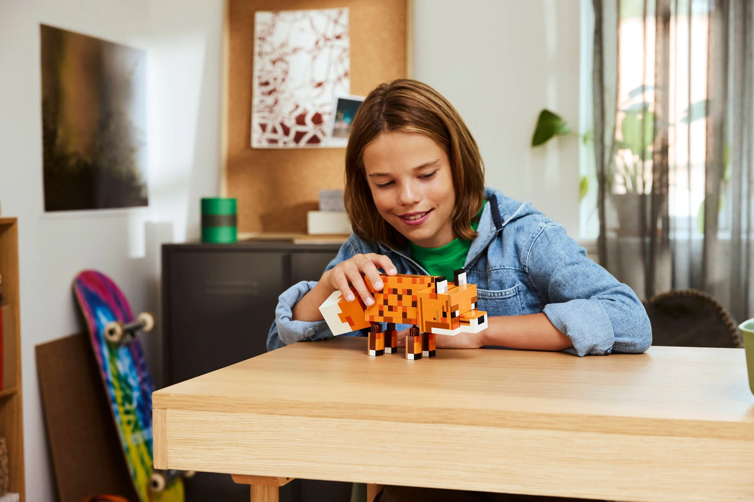 Copil se joacă cu setul LEGO Minecraft Vulpea (21588) pe o masă de lemn.