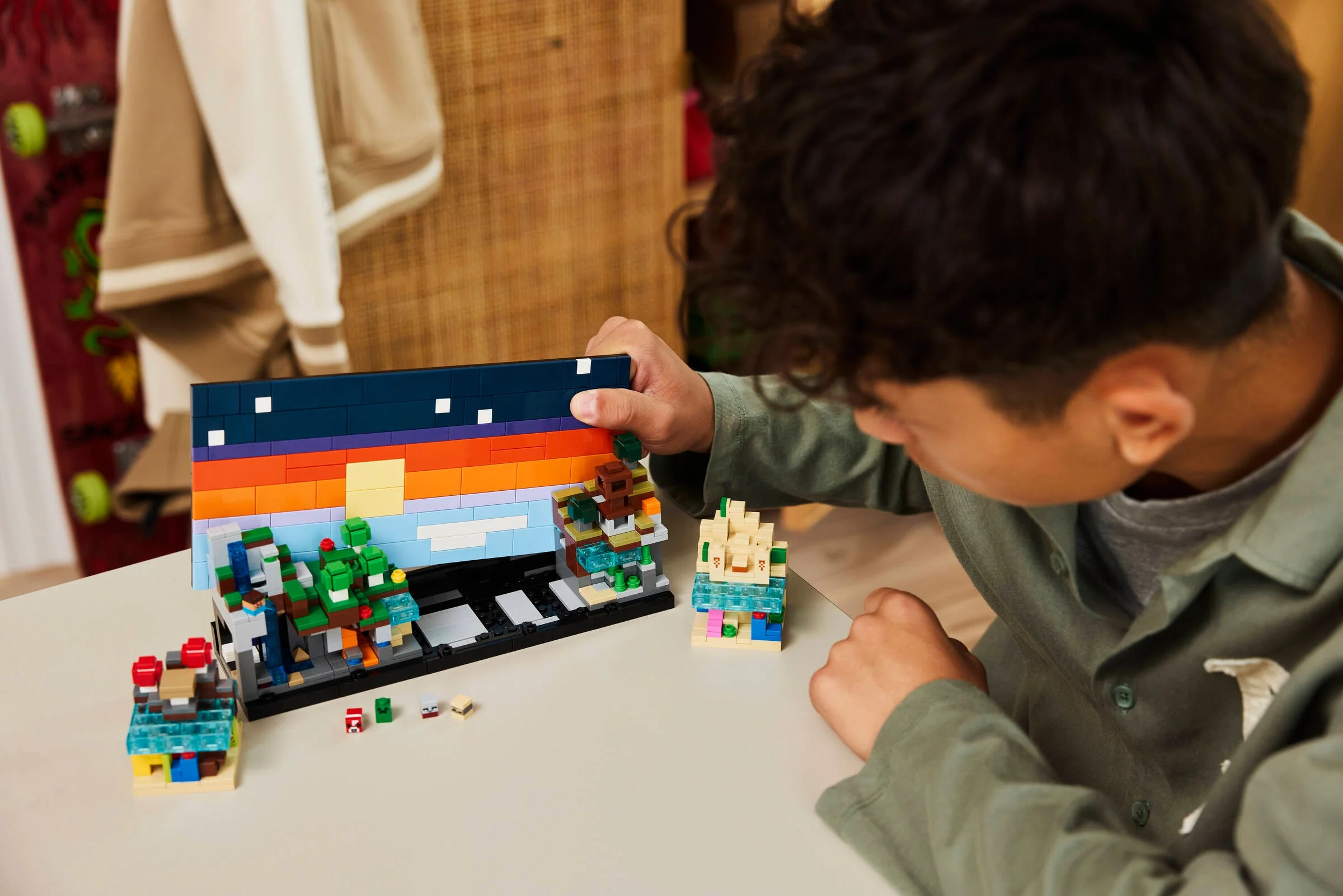 Copil construind setul LEGO Minecraft Mini Biomes. Scene detaliate cu peisaje și elemente Minecraft.