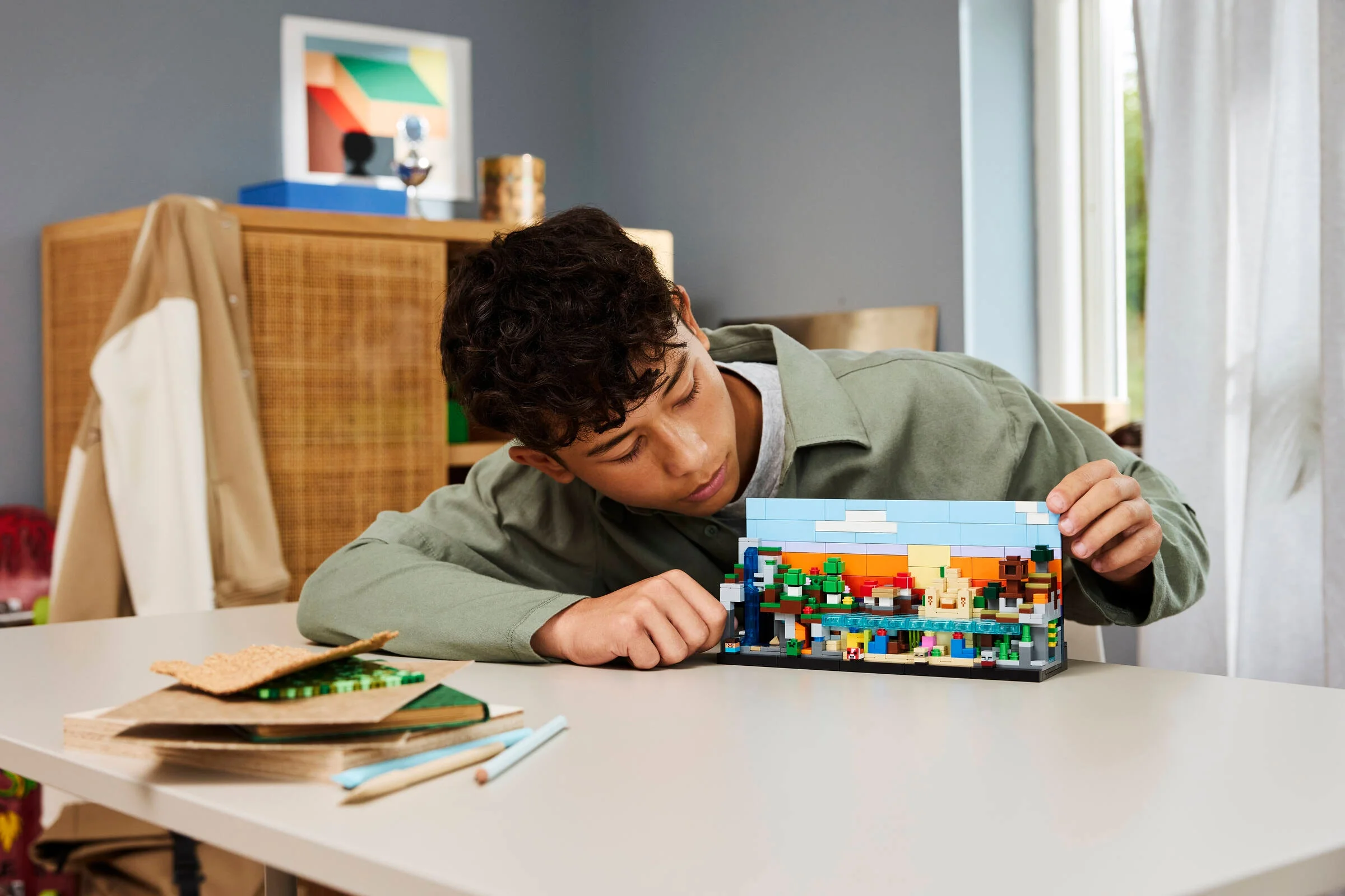 Un tânăr admiră bioma Minecraft LEGO, concentrat pe detalii. O scenă captivantă cu modelul finalizat.