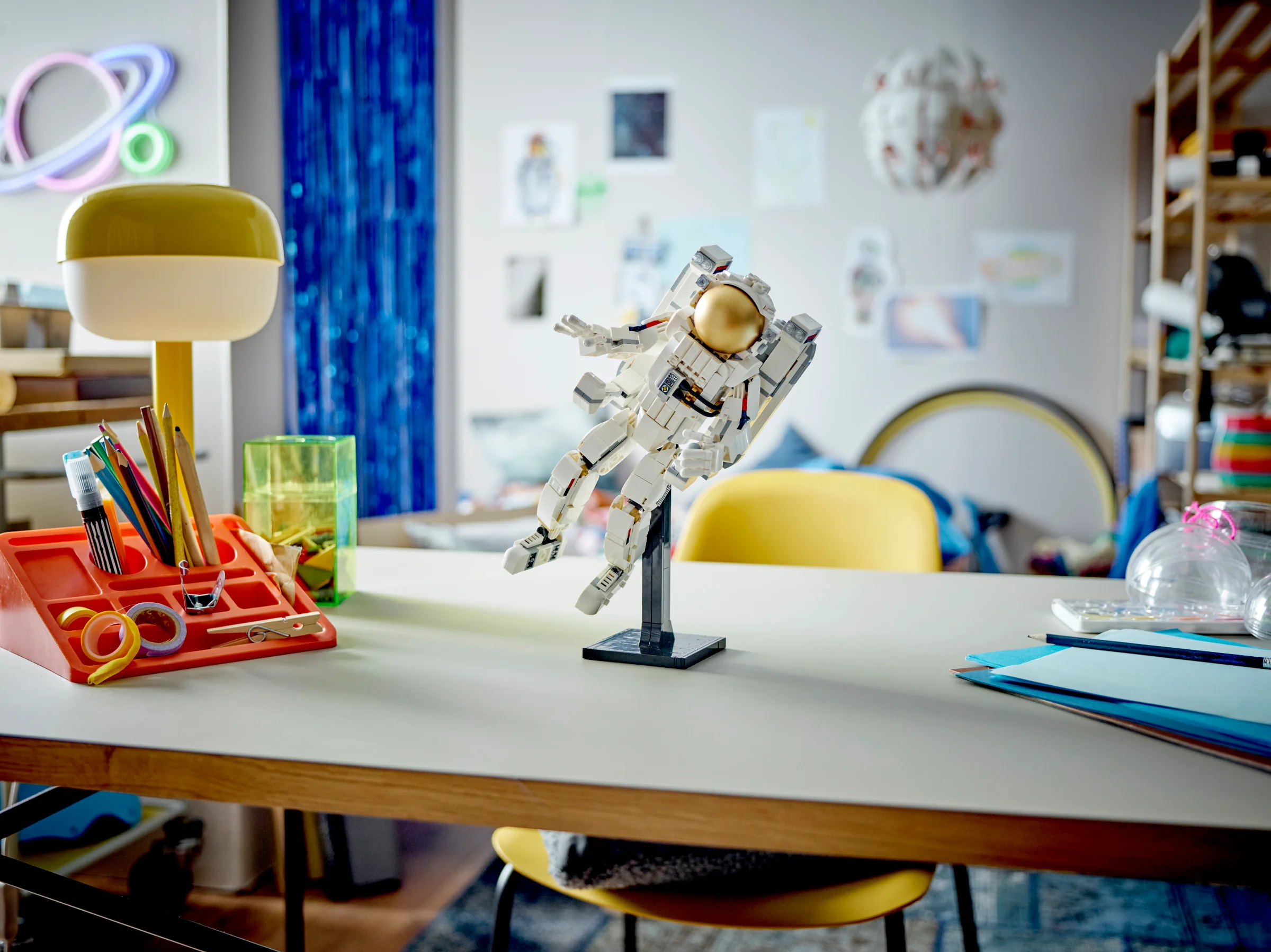 Astronaut LEGO 31152 pe un birou, într-o cameră de copil decorată tematic.