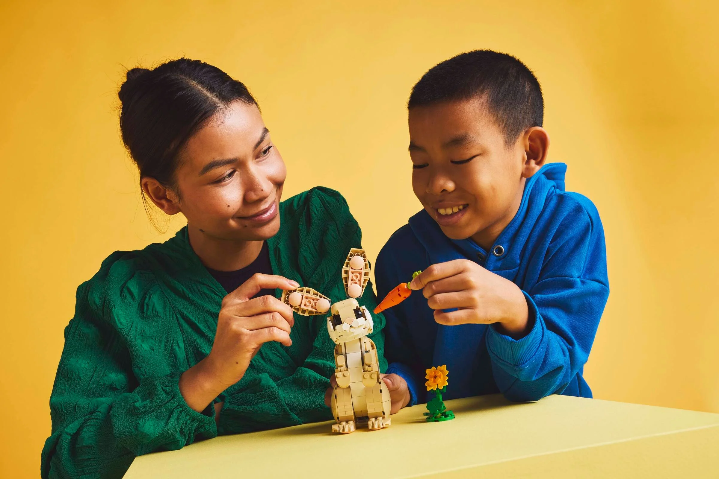 Copil și femeie interacționând cu setul Lego Iepuraș drăguț, construind cu zâmbetul pe buze.