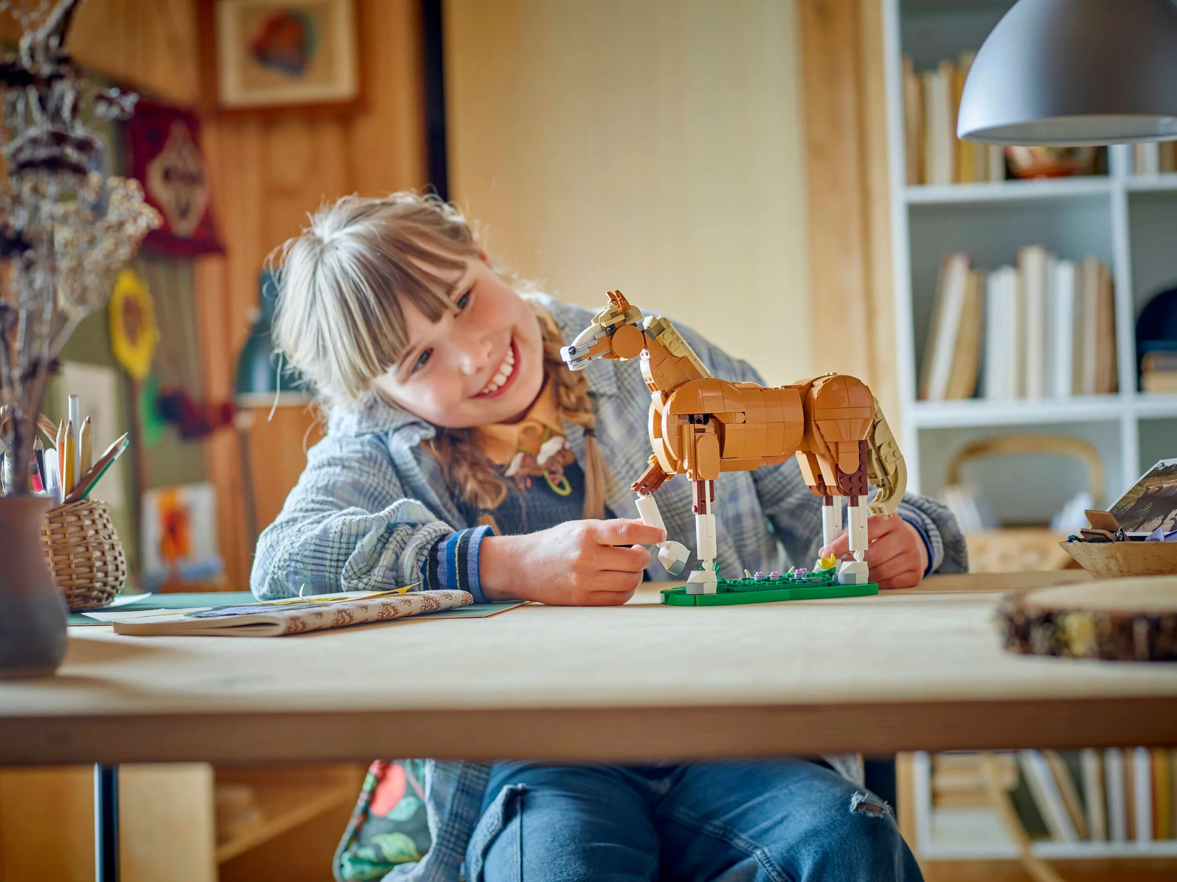 Fetiță zâmbitoare construind un cal LEGO Creator frumos, maro. Scene drăguță.