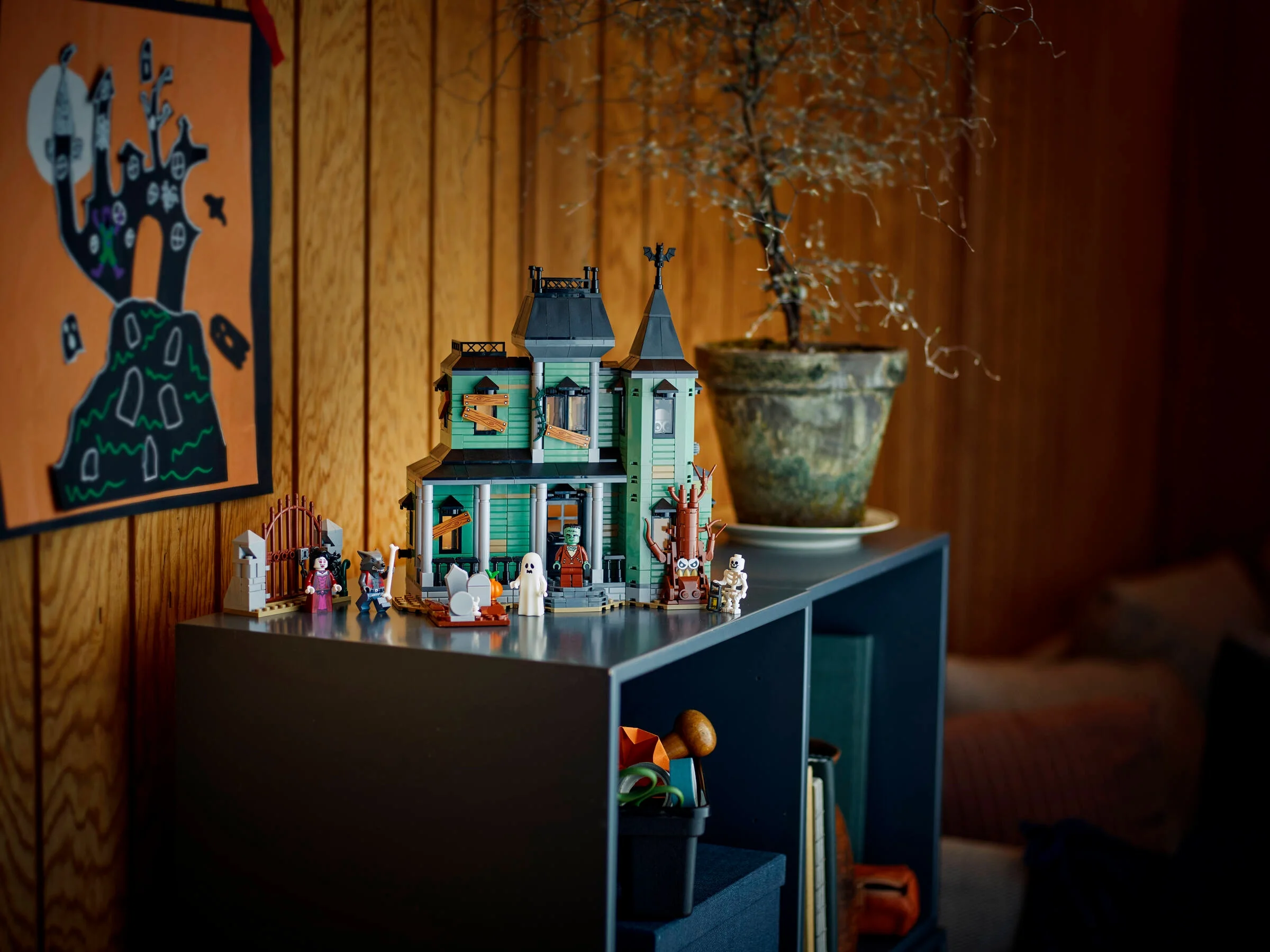 Imagine cu Conacul Bântuit LEGO Creator (31167) și minifigurinele pe un raft, într-un decor de Halloween.