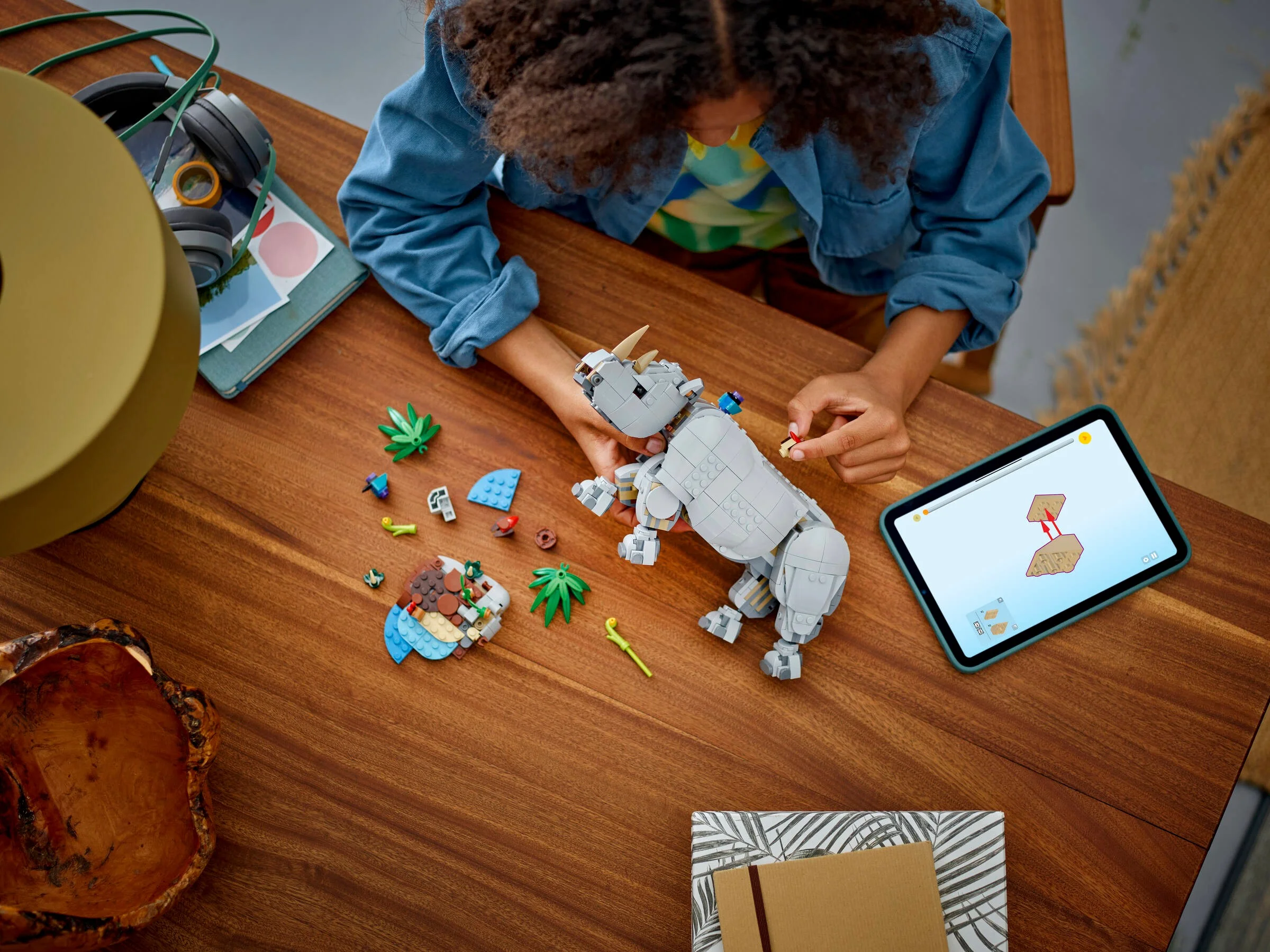 Imagine cu un copil asamblând rinocerul LEGO 31171, urmând instrucțiunile de pe tabletă.