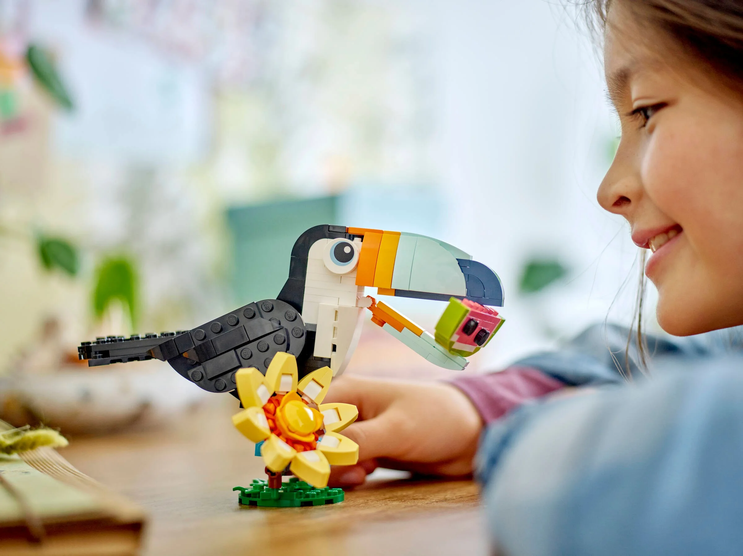 Un copil admiră un tucan tropical LEGO Creator. Jucăria este colorată și detaliată.