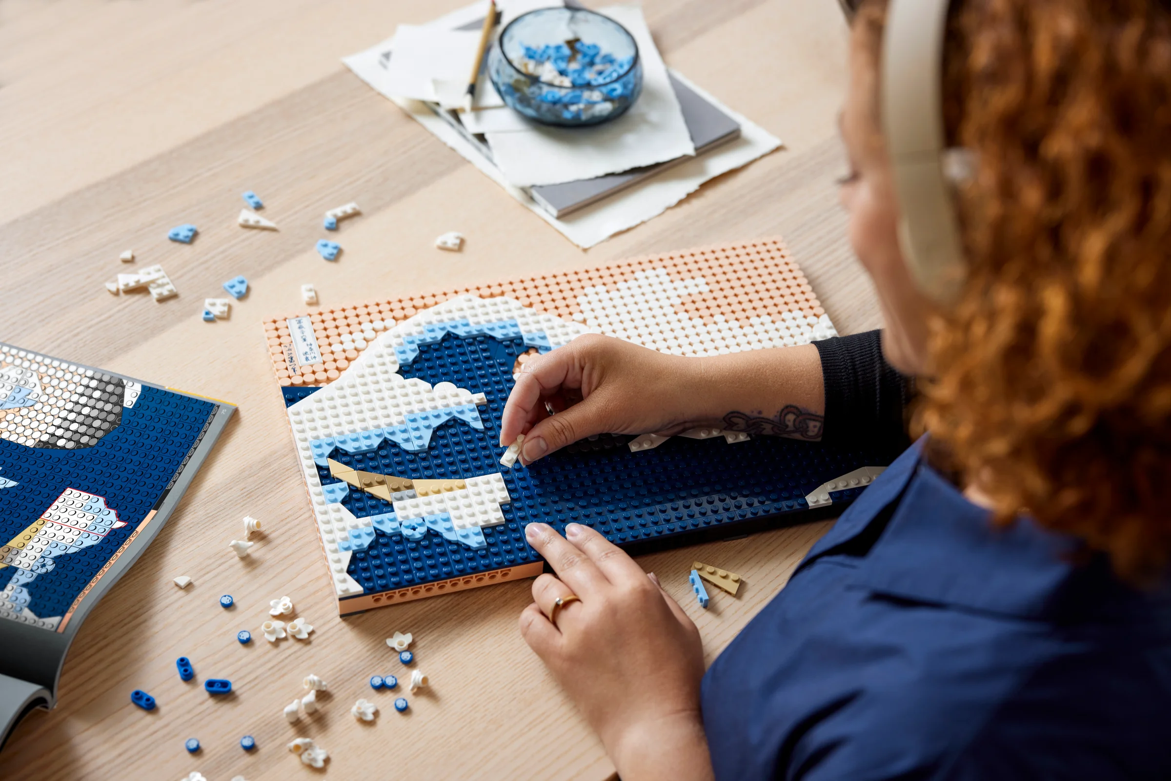 O persoană construiește un tablou LEGO cu valuri albastre și albe, setul Hokusai.