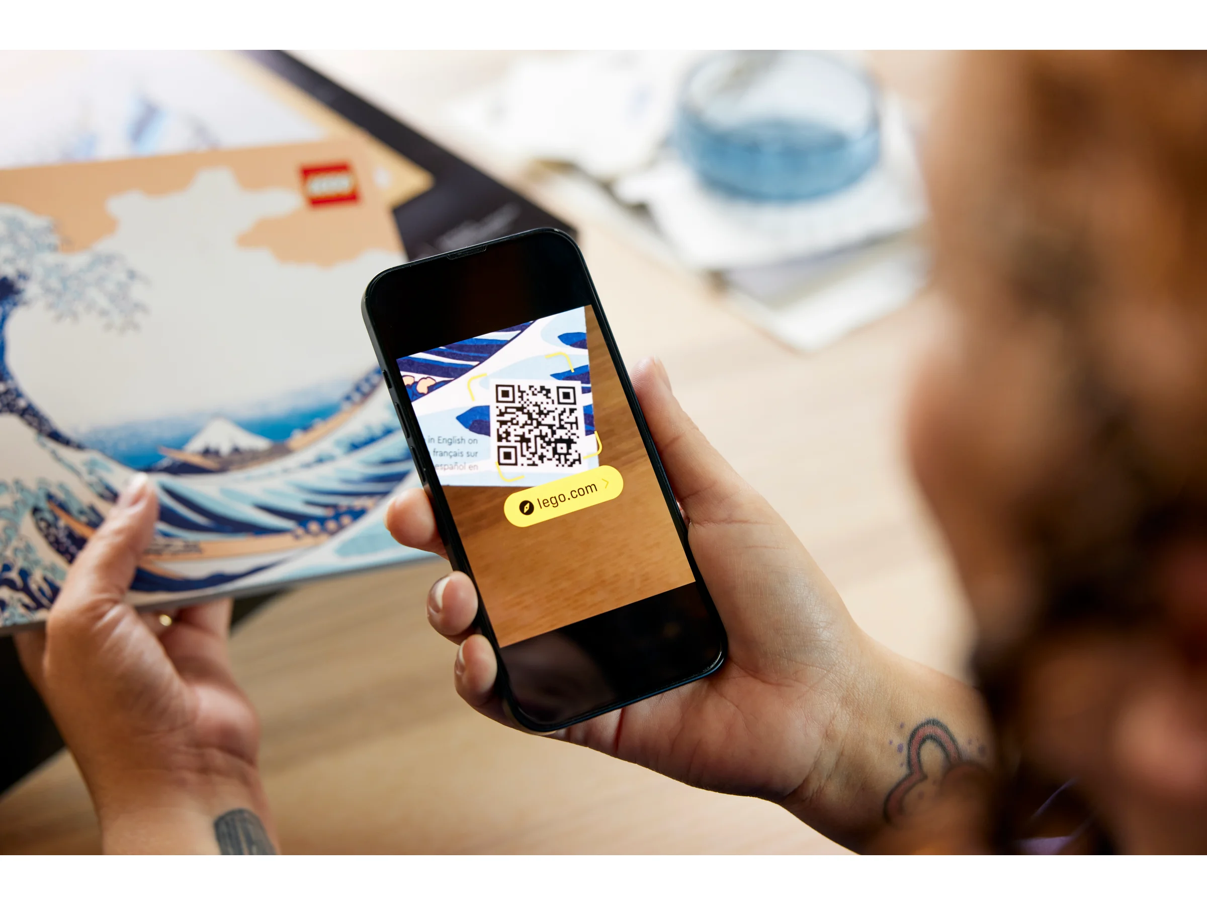 O persoană scanează codul QR de pe setul LEGO Hokusai.