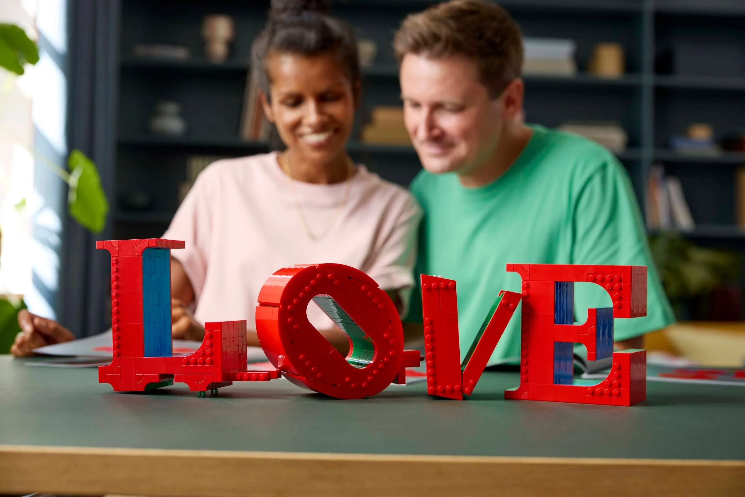 Un cuplu zâmbește privind construcția LEGO LOVE. Detaliile modelului sunt vizibile.