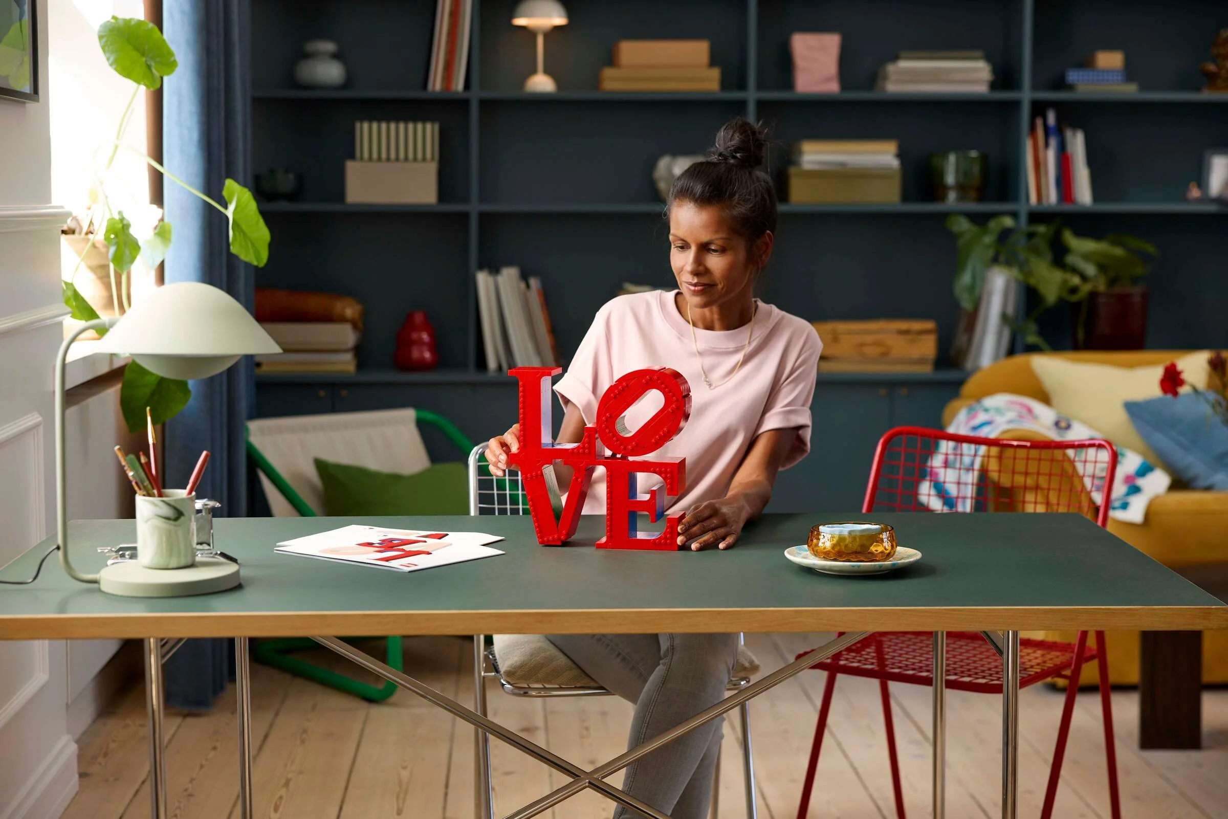 Imagine cu o femeie aranjând modelul LEGO LOVE, într-un cadru casnic, luminos și modern.