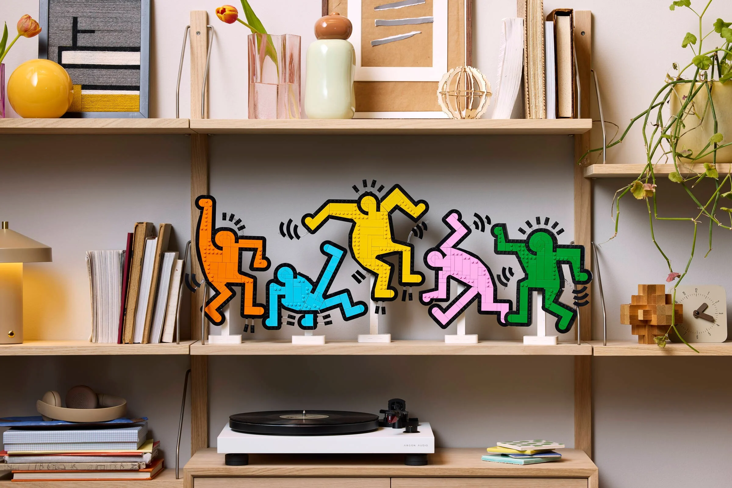Modelul LEGO Dancing Figures, în culori vii, expus pe un raft elegant.