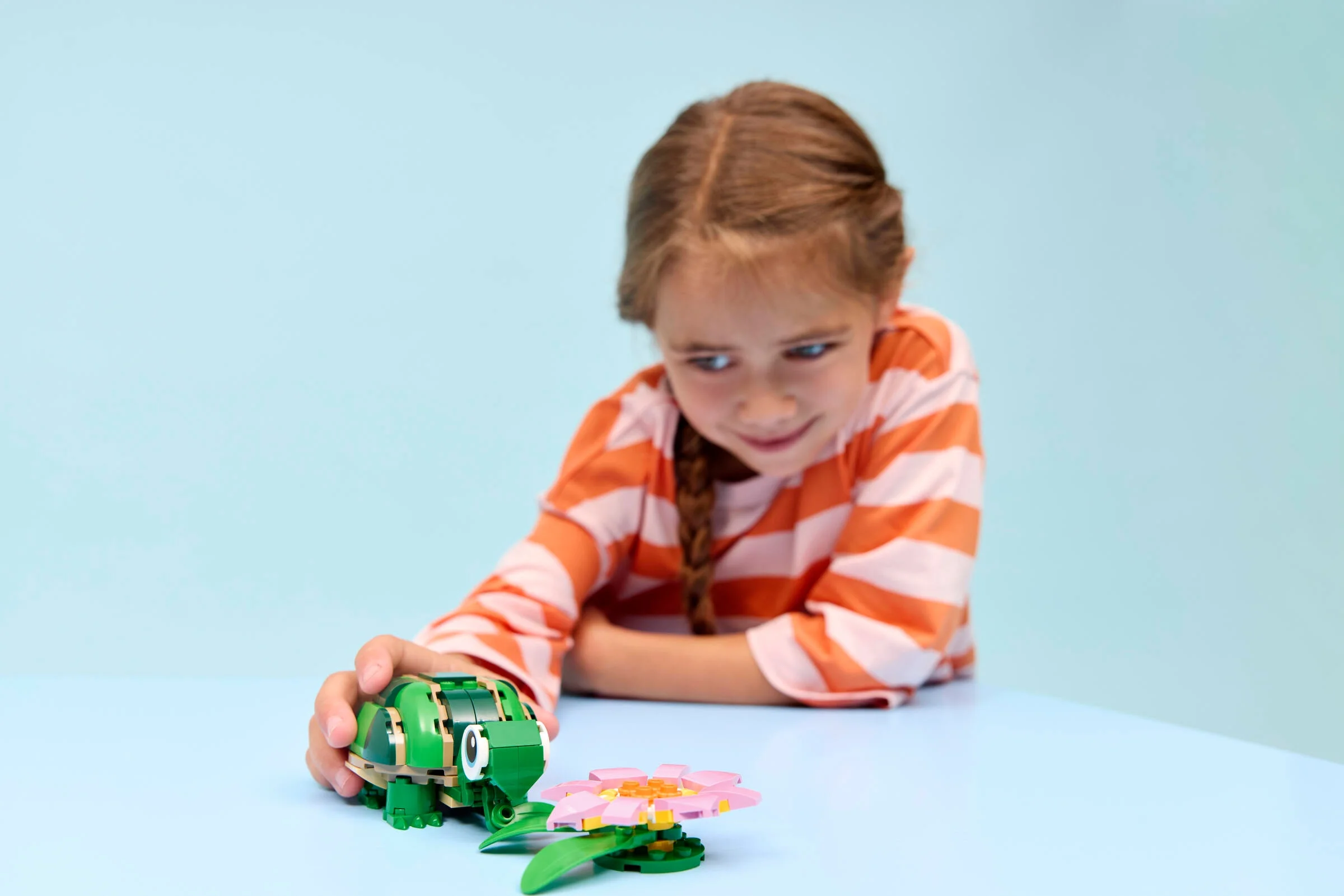 Fată interacționând cu setul LEGO broască țestoasă și nufăr. Joc creativ și distractiv.