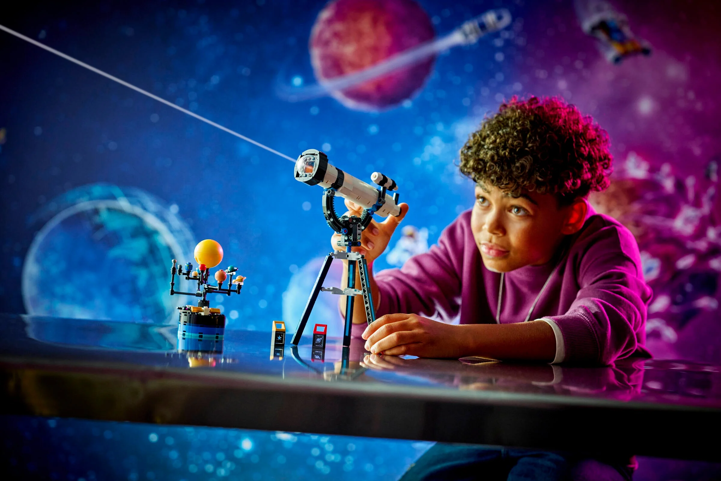 Copil explorează spațiul cu telescopul și modelul sistemului solar LEGO Creator.