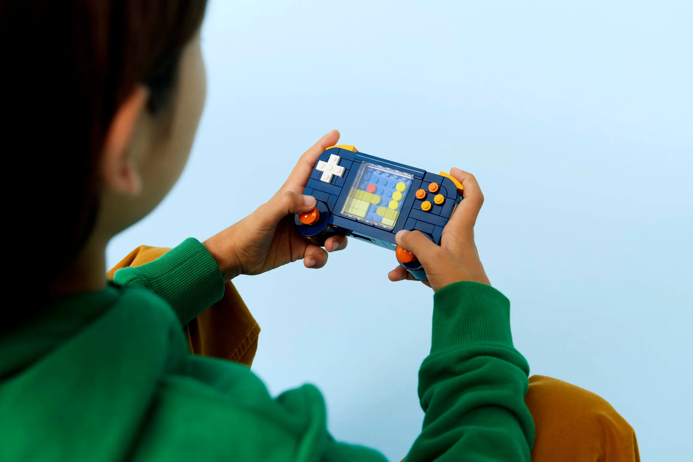 Imagine cu un copil care se joacă cu consola retro LEGO, arătând ecranul cu jocul.
