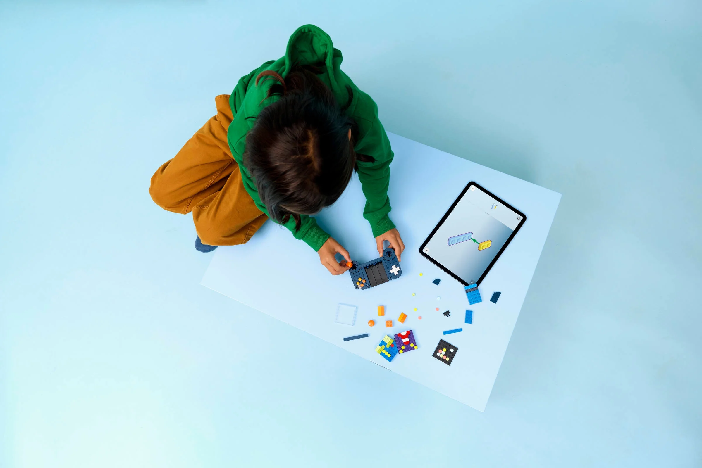 O fată construiește consola retro LEGO cu ajutorul instrucțiunilor de pe tabletă.