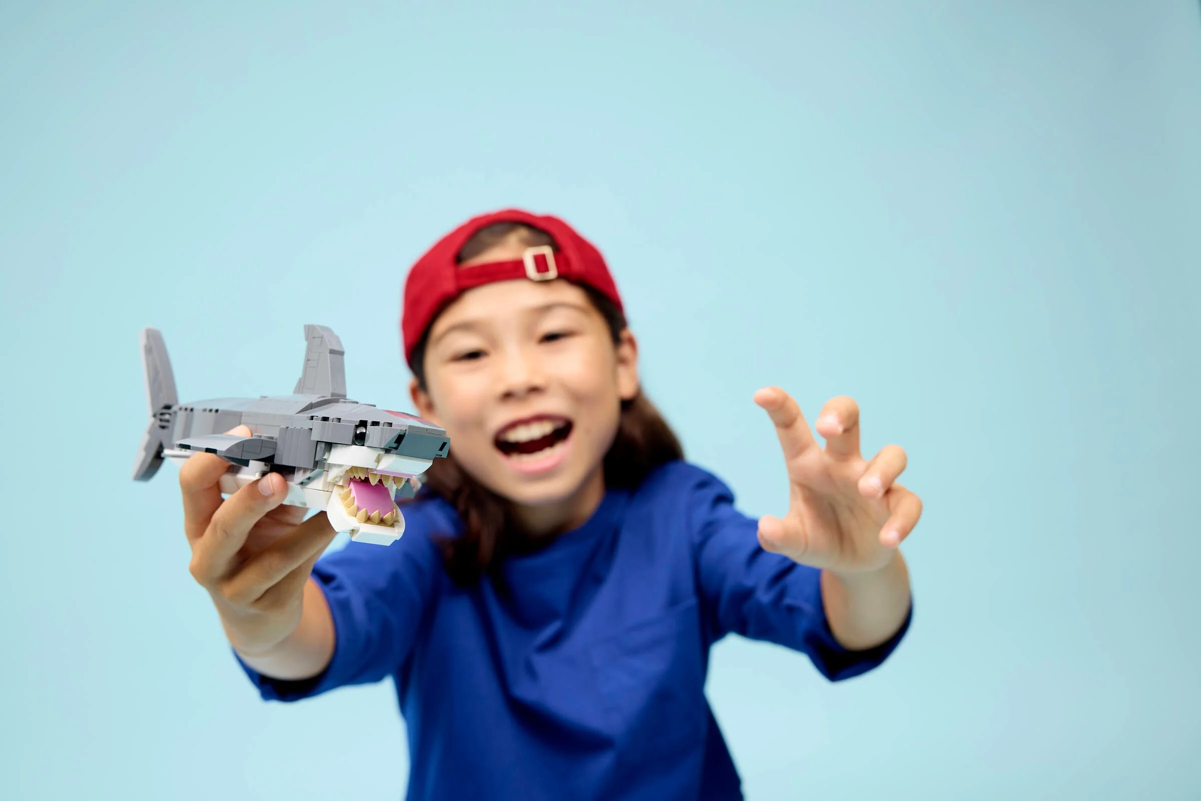 Copil se joacă cu rechinul LEGO Creator, părând entuziasmat. Distracție garantată!