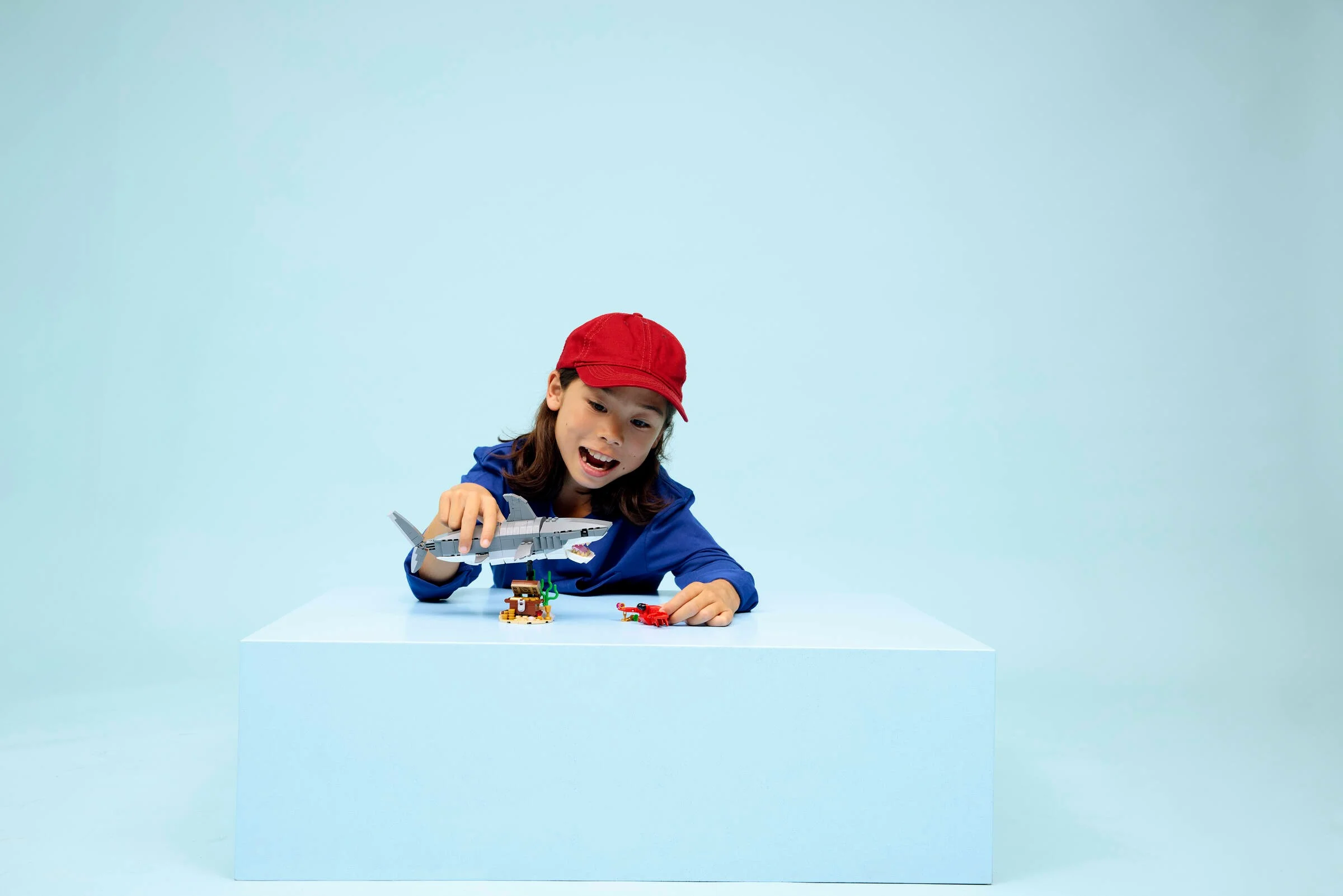 Copil jucându-se cu setul LEGO Creator Rechin Feroce și Cufărul cu Comori.