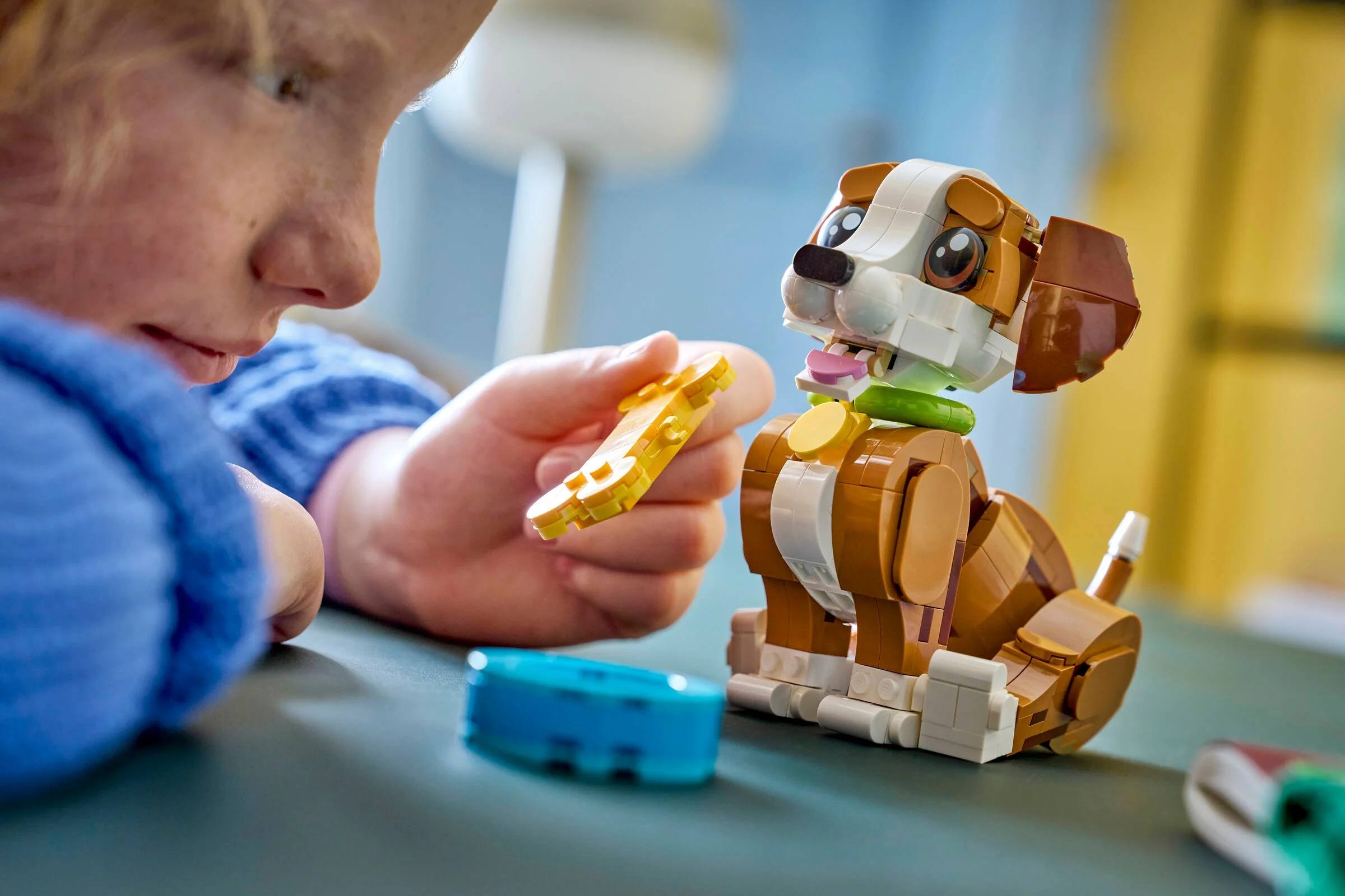 Copil interacționând cu cățelușul LEGO Creator 31382, oferindu-i un os de jucărie.