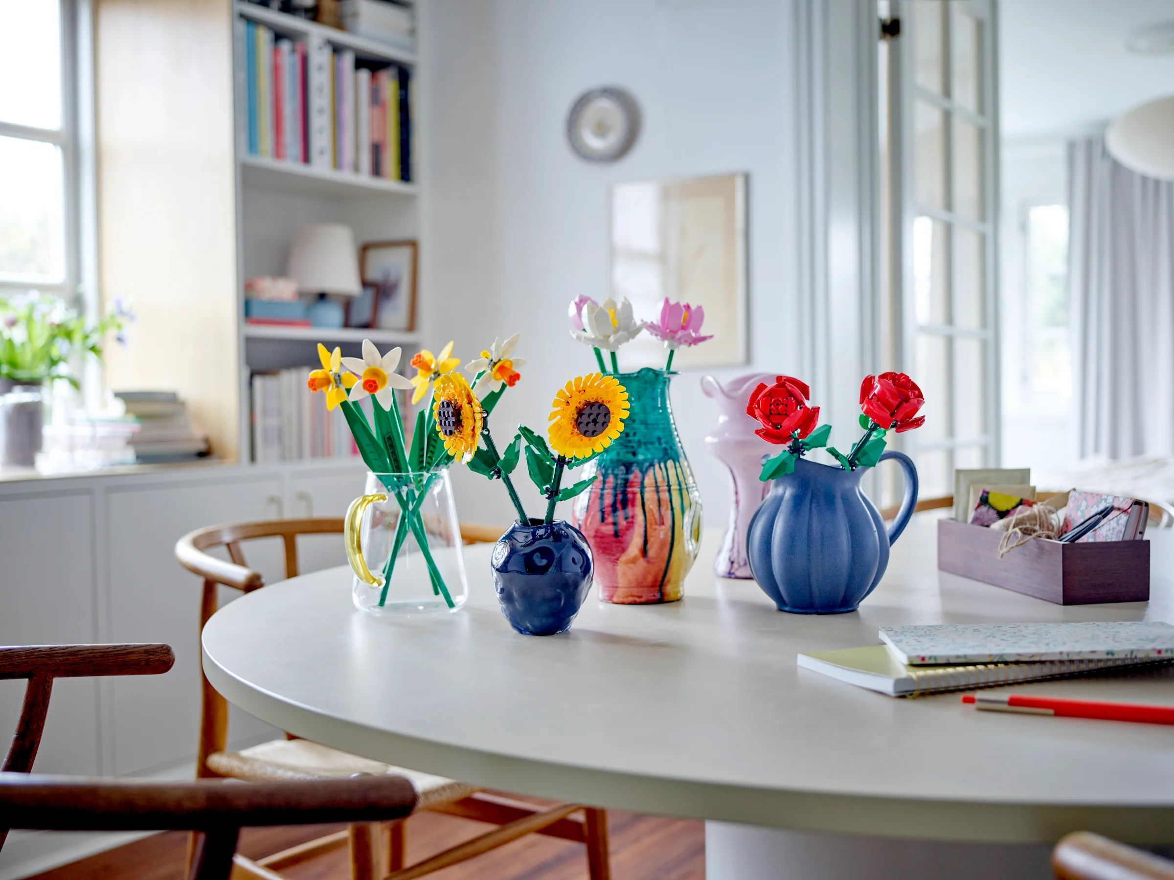 Aranjament floral LEGO cu narcise, floarea-soarelui, lotus, și trandafiri, într-un decor casnic.