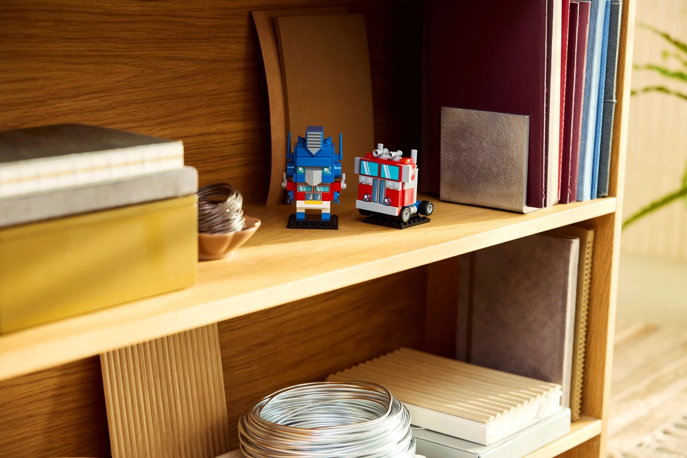 Setul LEGO BrickHeadz Optimus Prime, robot și camion, expuse pe o etajeră. O jucărie creativă pentru fani.