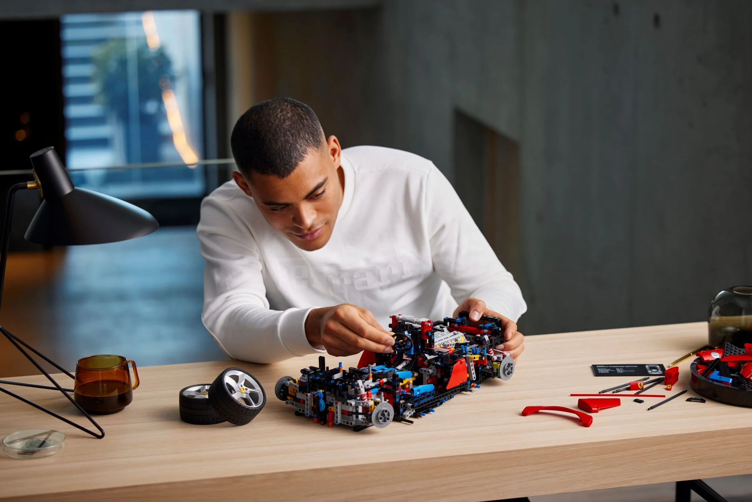 Bărbat construind modelul LEGO Ferrari Daytona SP3. Detalii ale construcției vizibile.